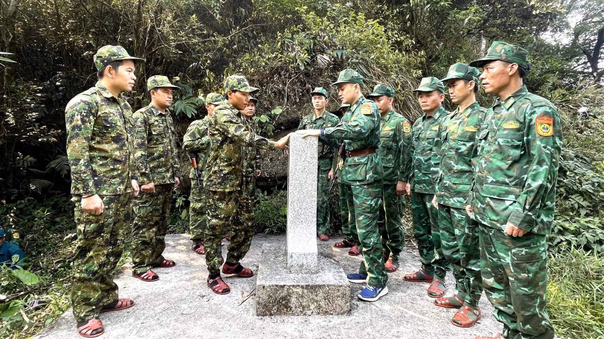 Sau một thời gian dài hành quân trong điều kiện thời tiết và khí hậu khắc nghiệt, lực lượng bảo vệ biên giới 2 tỉnh của Việt Nam và Lào đến được cột mốc số 522 nằm ở vị trí cao nhất trên đỉnh núi Giăng Màn, cao gần 2.000m so mực nước biển. Trong ảnh: Lực lượng 2 bên làm thủ tục đầu tiên chạm vào cột mốc quốc giới.