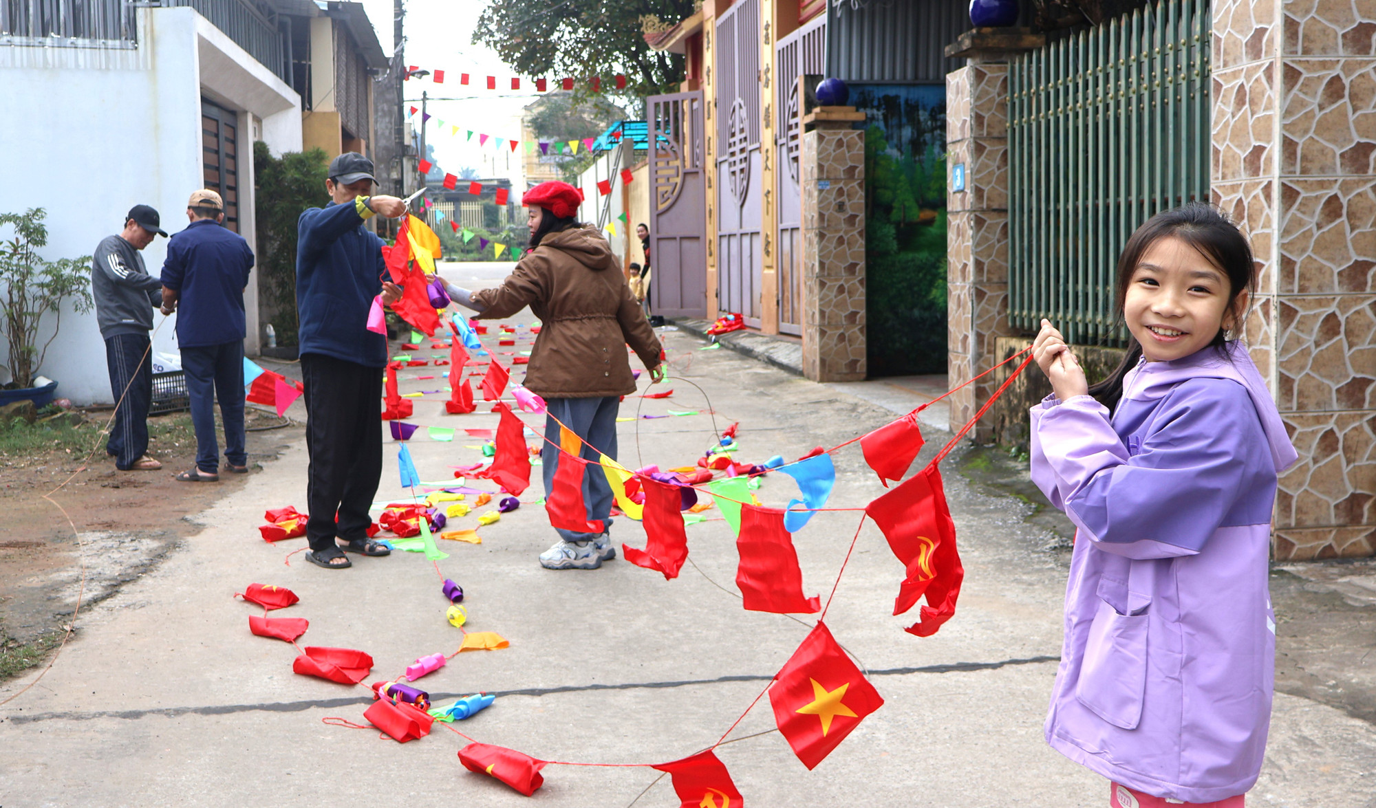 Em bé cũng vui với việc giăng và giữ dây cờ để cho người lớn buộc.