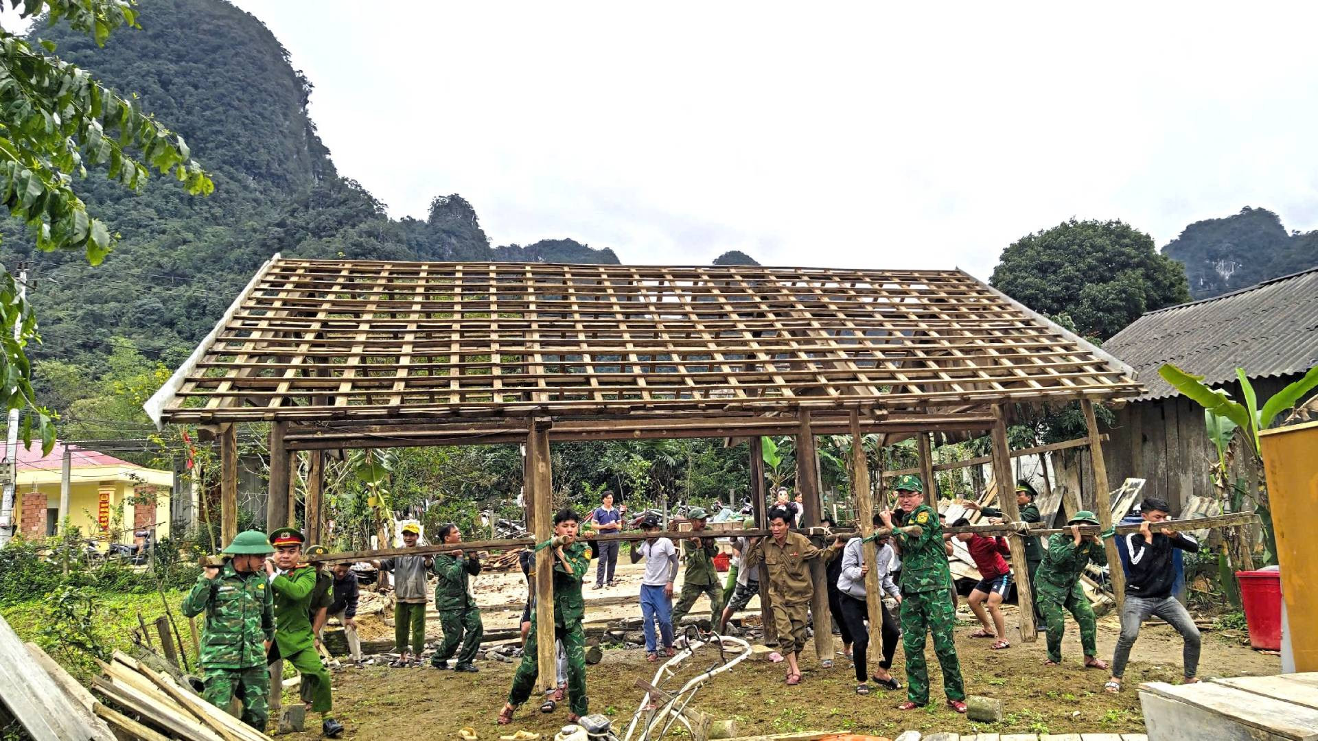 Bộ đội Biên phòng, Công an xã cùng lực lượng xung kích ở xã Thượng Hóa hợp sức khiêng bộ khung nhà cũ để lấy nền làm nhà mới.