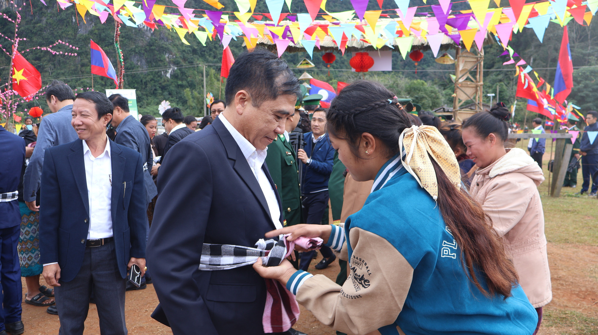 Phụ nữ người Lào buộc hoặc quàng một chiếc khăn truyền thống của người Lào cho khách đến thăm.