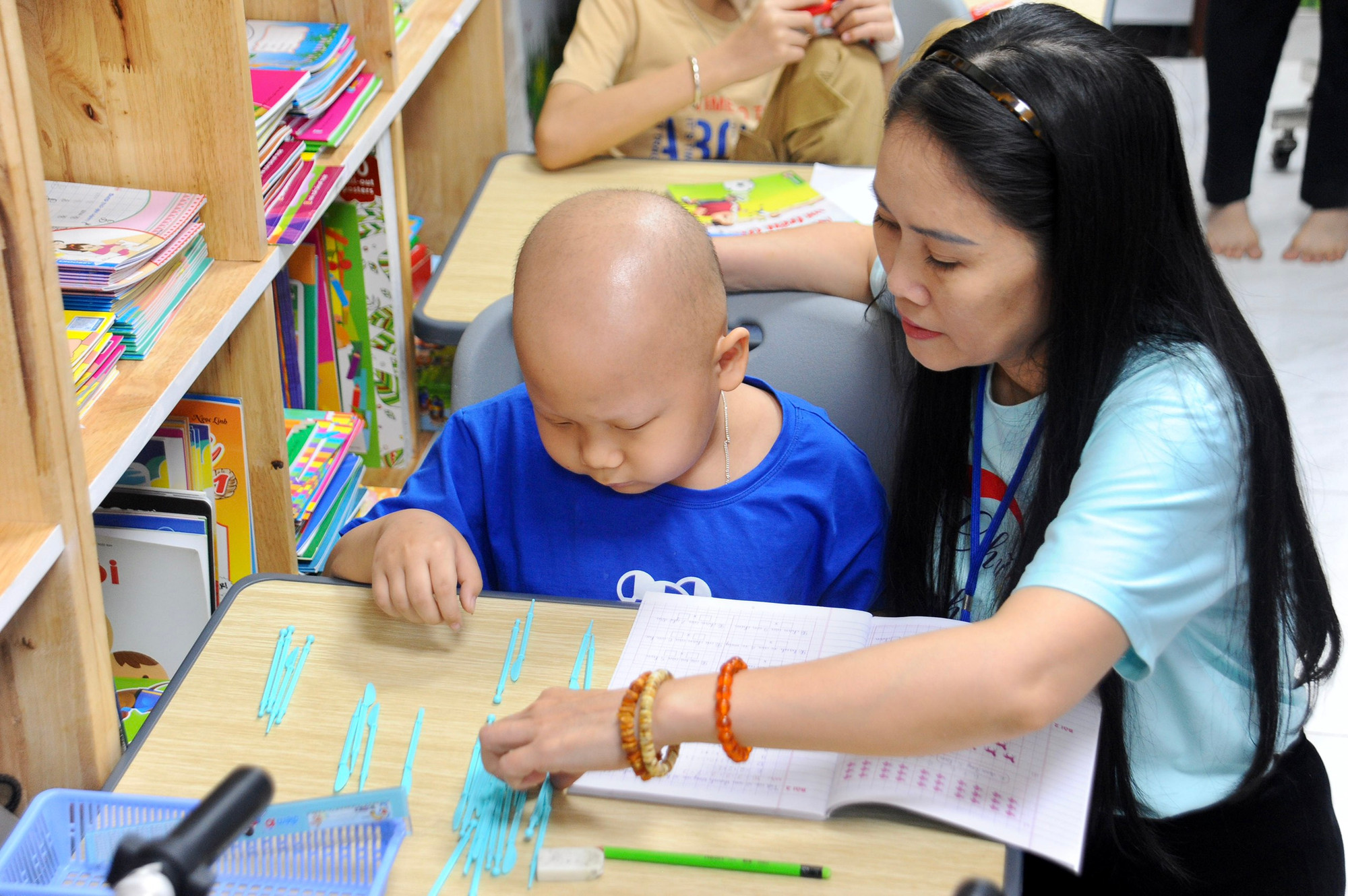 Chị Mai ân cần hướng dẫn bài tập cho một trẻ mắc ung thư.