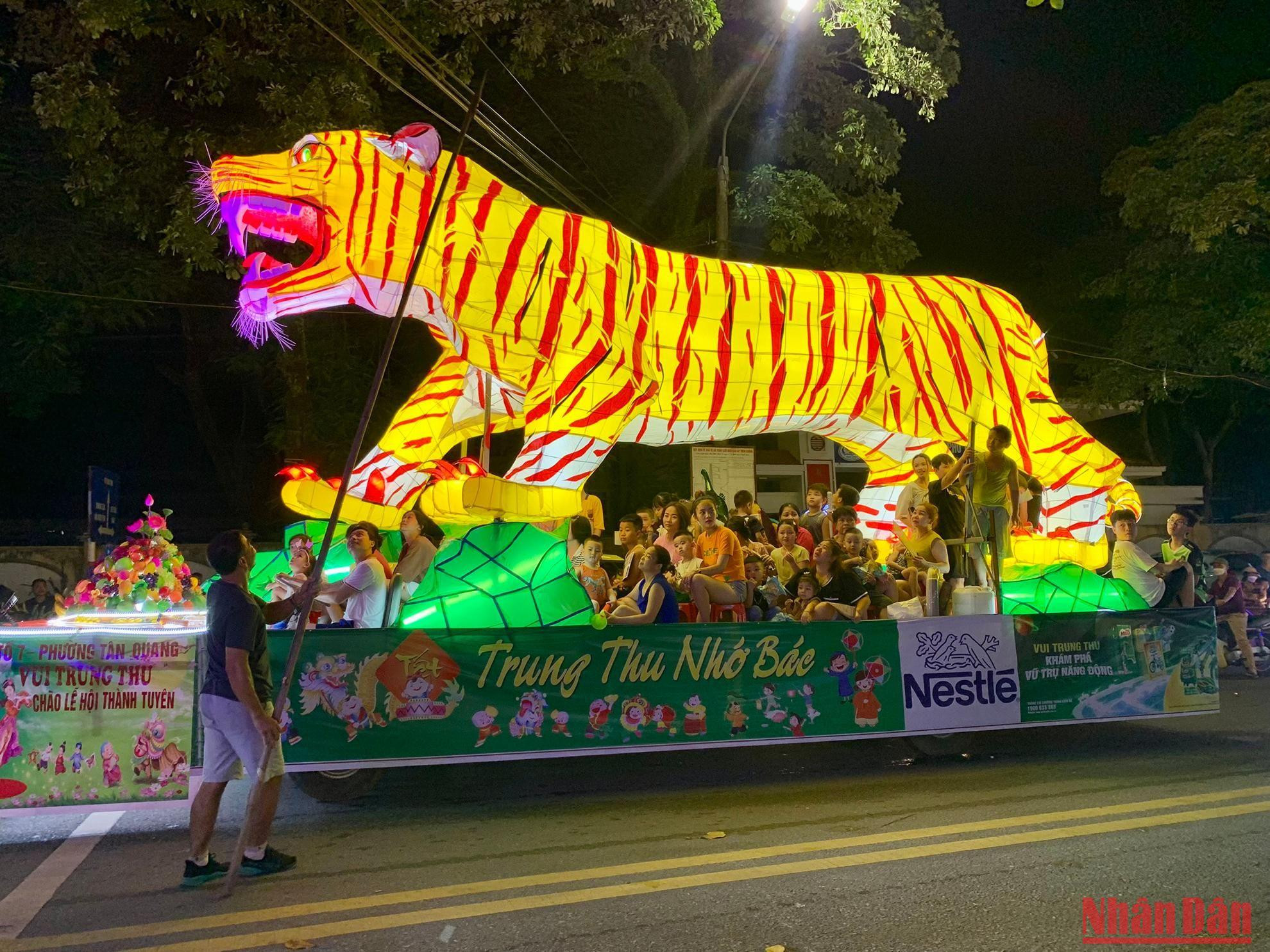 Vì hình “ông Hổ” quá cao nên một phụ huynh phải mang theo cây sào để nâng các đường dây điện trên phố cho khỏi vướng. Cách người dân xử lý sự cố gặp phải khi rước những chiếc đèn khổng lồ cũng thật thú vị.