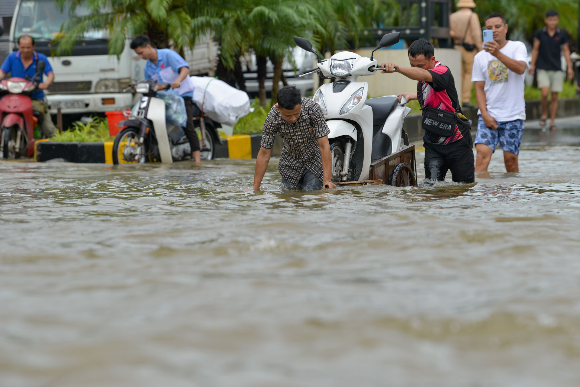 Nhiều người tận dụng khi đường ngập để kiếm thêm thu nhập bằng cách kéo xe máy hoặc người đi qua các điểm ngập sâu.