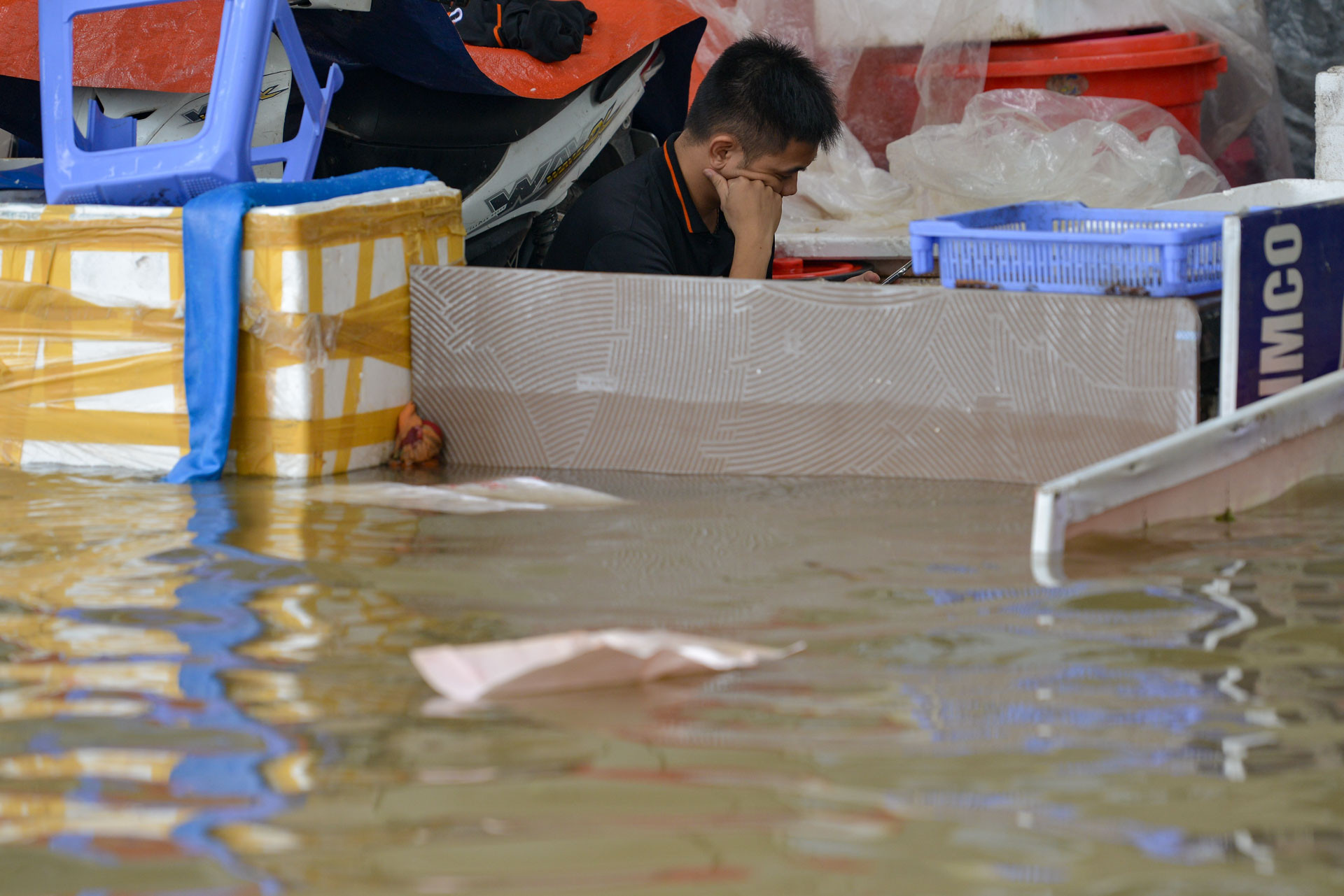 Ở phía ngoài mặt đường Hoàng Tùng, nhiều hầm các căn biệt thự liền kề chìm trong nước, người dân phải dùng các vật dụng để chắn nước tràn vào.