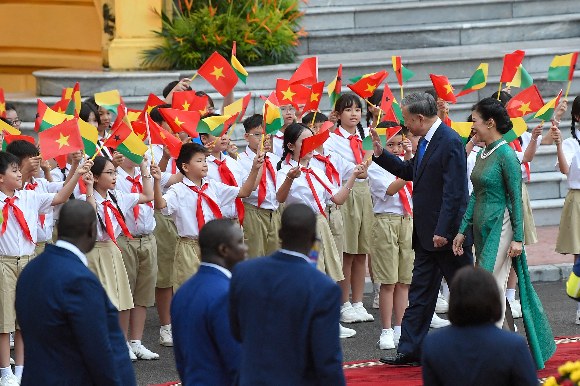 Tổng Bí thư, Chủ tịch nước Tô Lâm cùng Phu nhân vẫy chào các em thiếu nhi tại lễ đón.
