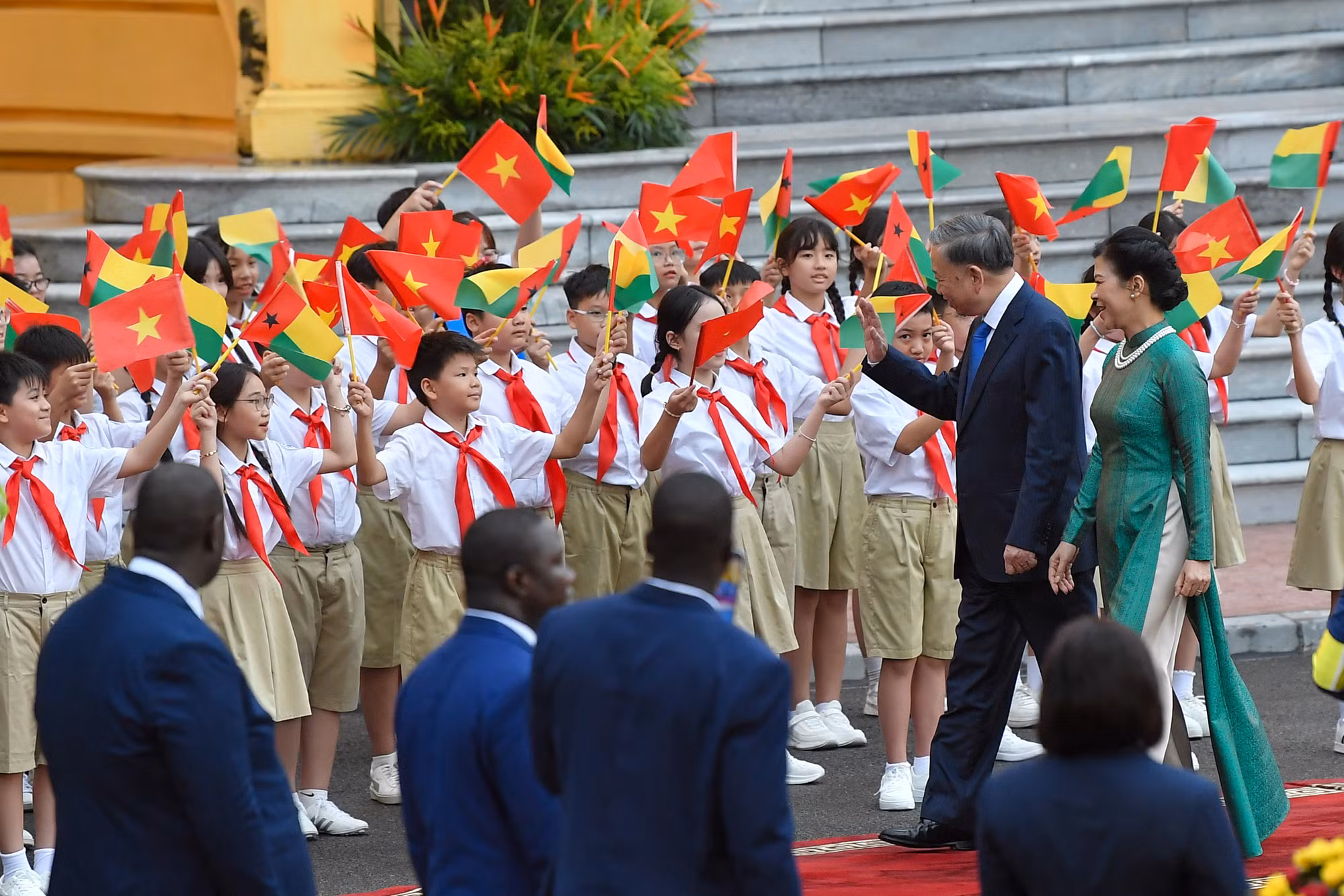 Tổng Bí thư, Chủ tịch nước Tô Lâm cùng Phu nhân vẫy chào các em thiếu nhi tại lễ đón.