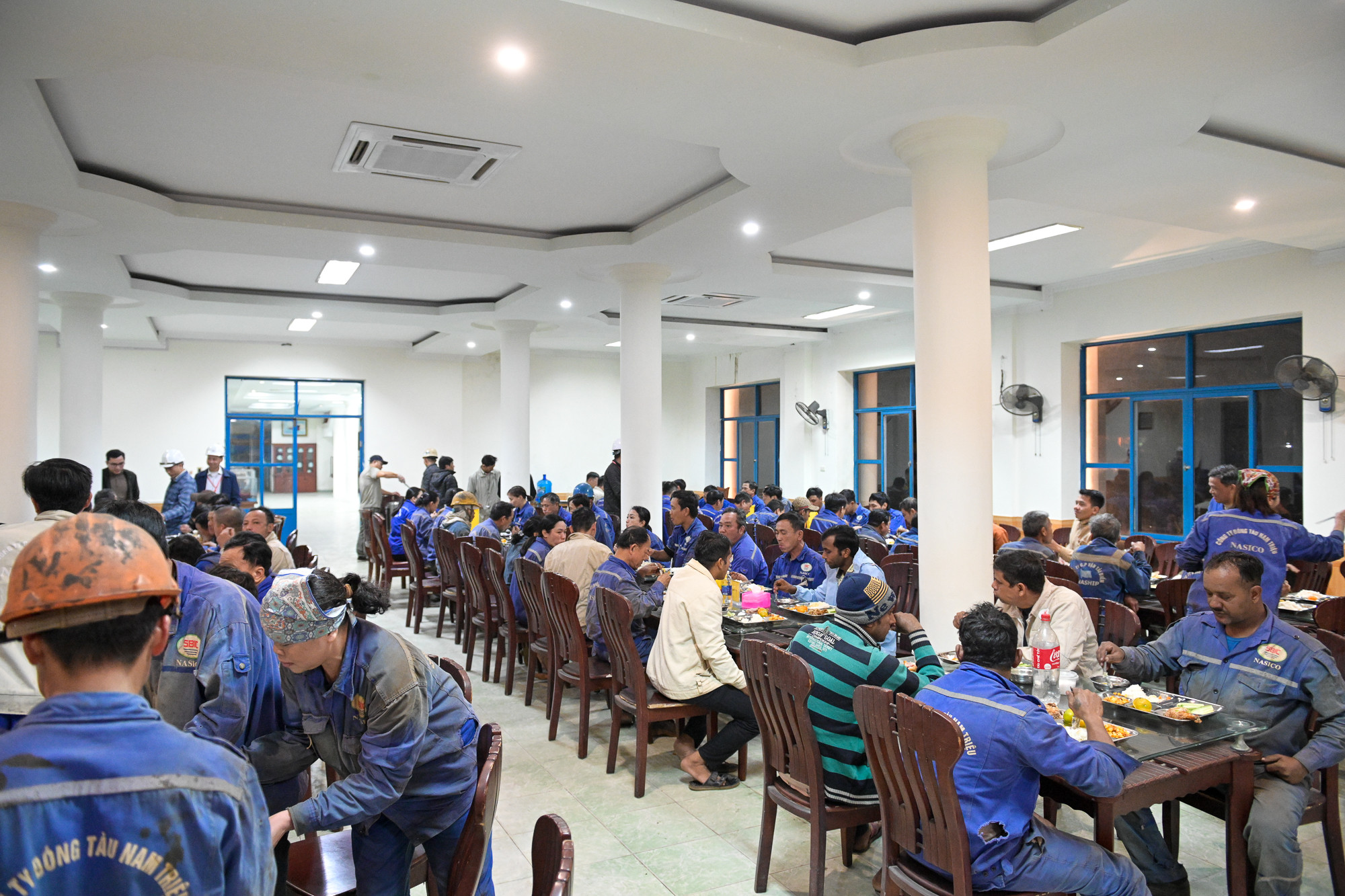 Sau giờ làm việc vất vả, những công nhân đóng tàu quây quần bên nhau ăn bữa tối. Sau giờ làm việc vất vả, những công nhân đóng tàu quây quần bên nhau ăn bữa tối.