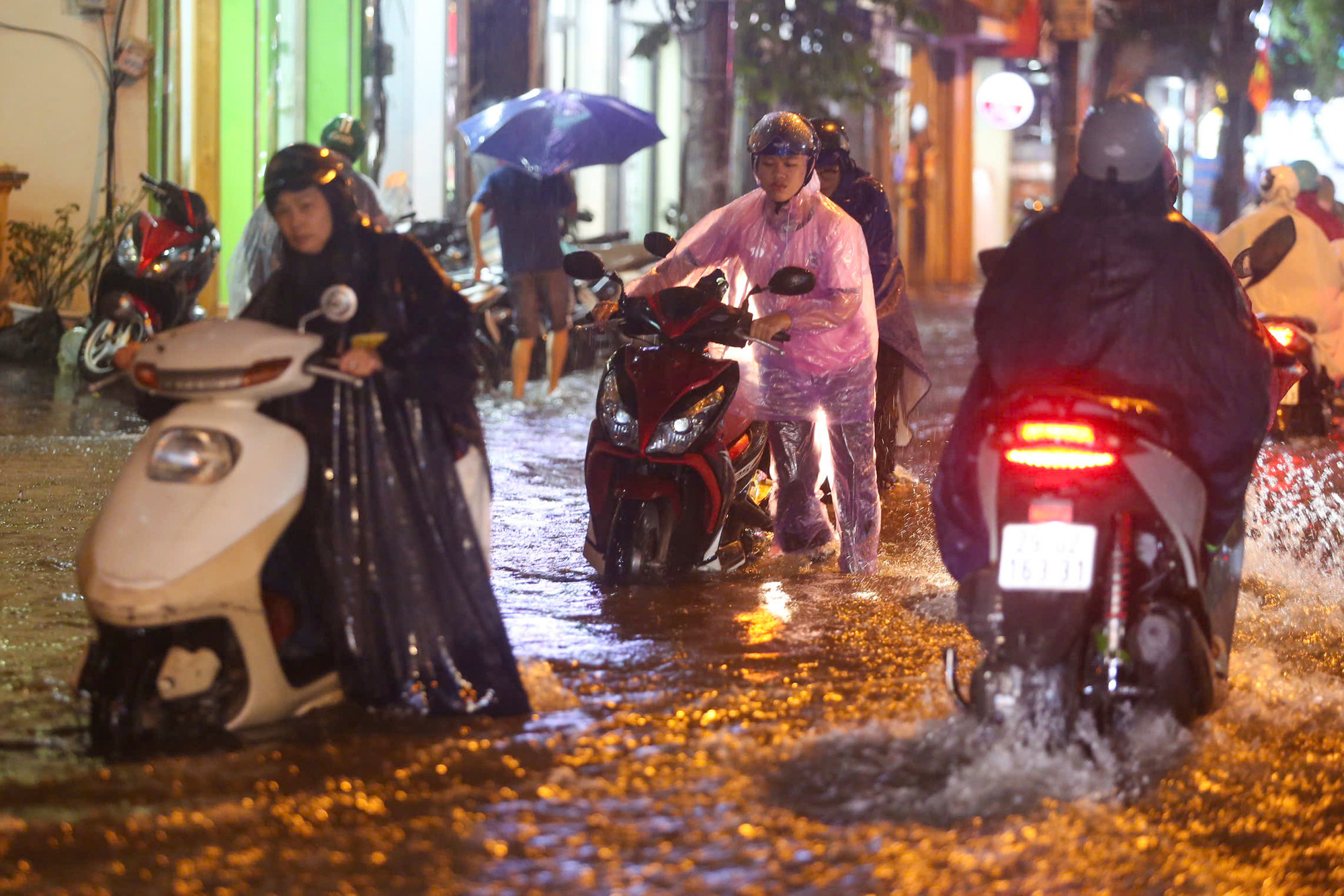 Người dân vất vả dắt xe máy qua khu vực ngập sâu trên phố Hoàng Văn Thái.