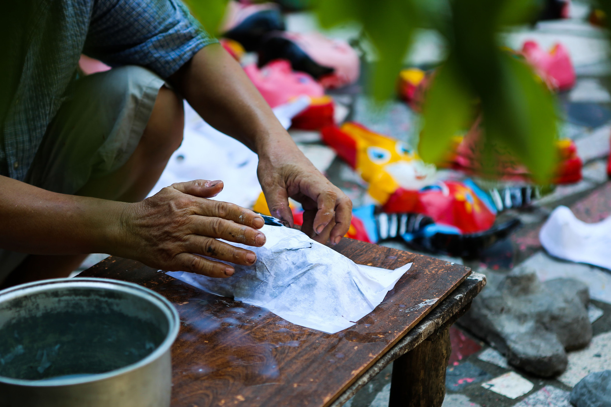 Mỗi chiếc mặt nạ được làm từ một chiếc khuôn xi-măng khác nhau, người thợ đặt từng lớp giấy lên và quét hồ.