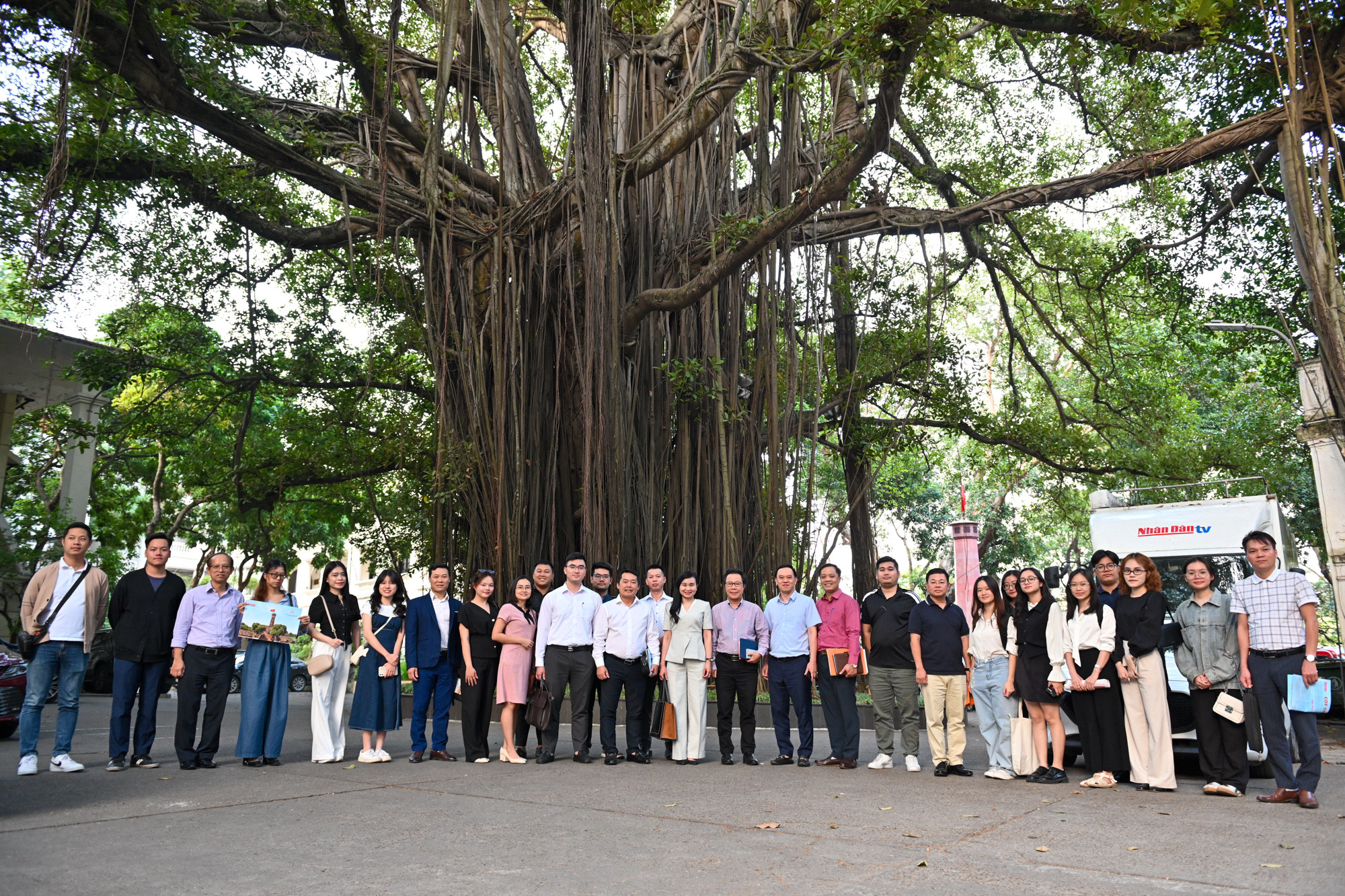 Lãnh đạo Báo Nhân Dân và các thành viên trong đoàn chụp ảnh lưu niệm bên cây đa cổ thụ trong khuôn viên Báo Nhân Dân.