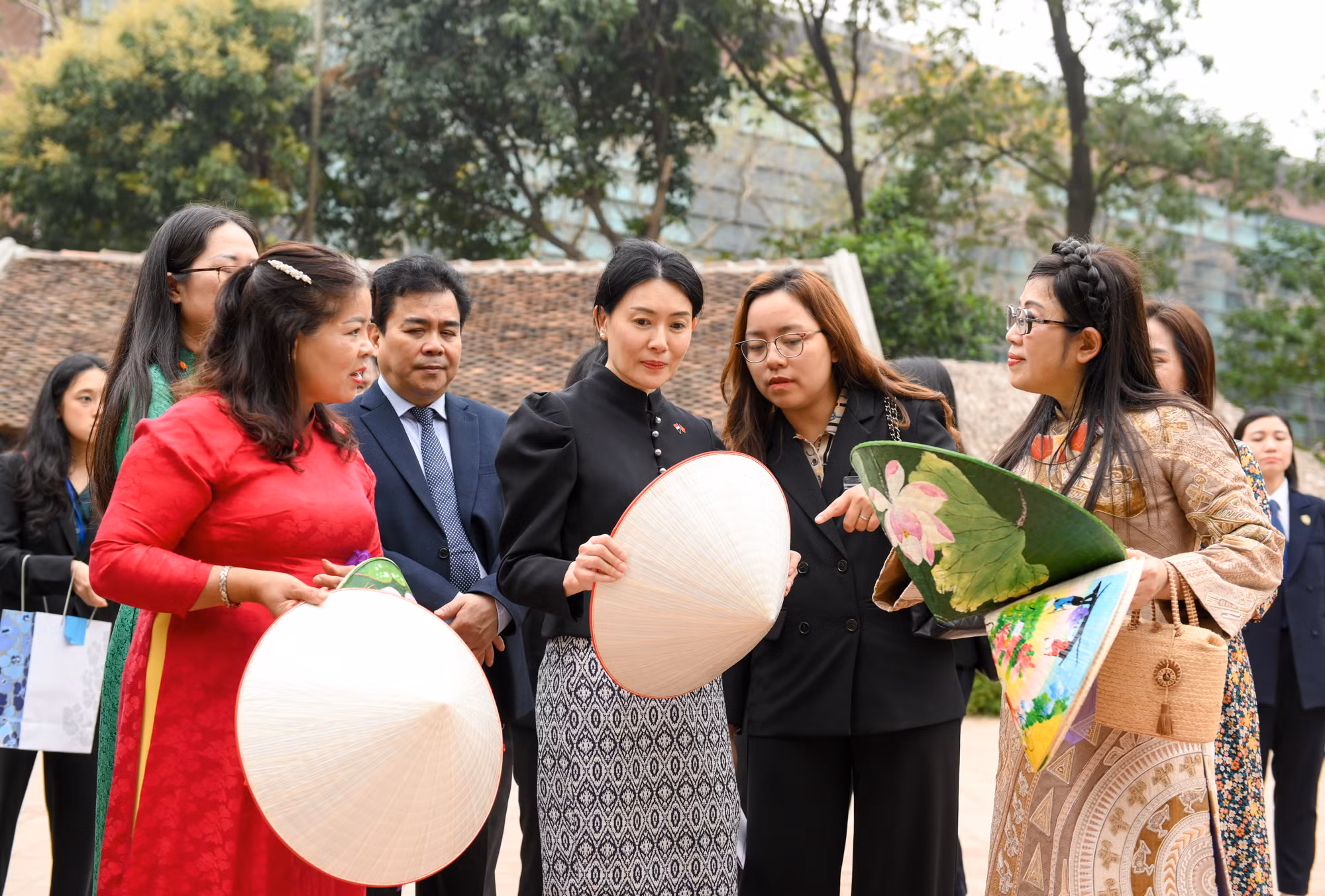 Nghệ nhân làng Chuông giới thiệu với hai phu nhân về nón lá truyền thống và sản phẩm nón lá mới của người Việt.