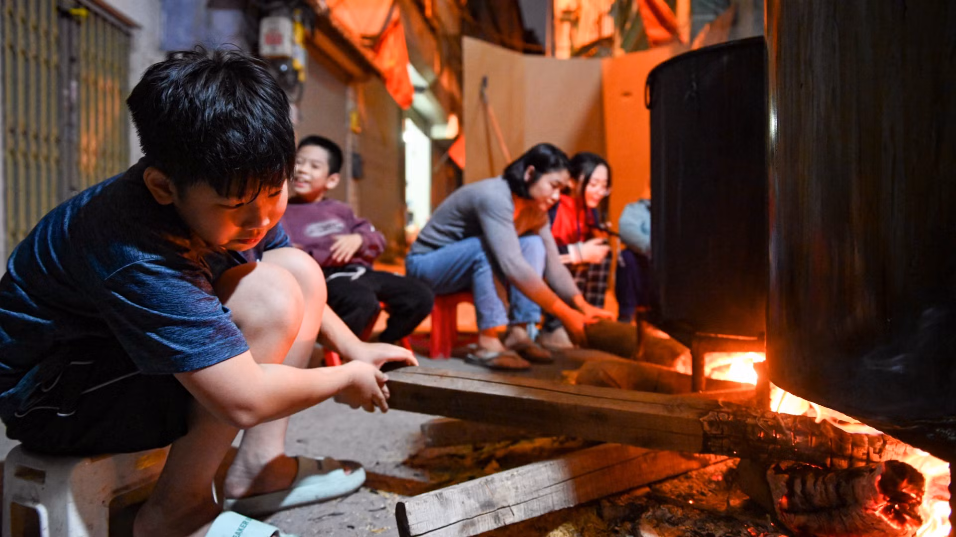 Người lớn, trẻ nhỏ quây quần, thức xuyên đêm trong nhiều con ngõ tại Hà Nội canh nồi bánh chưng Tết.