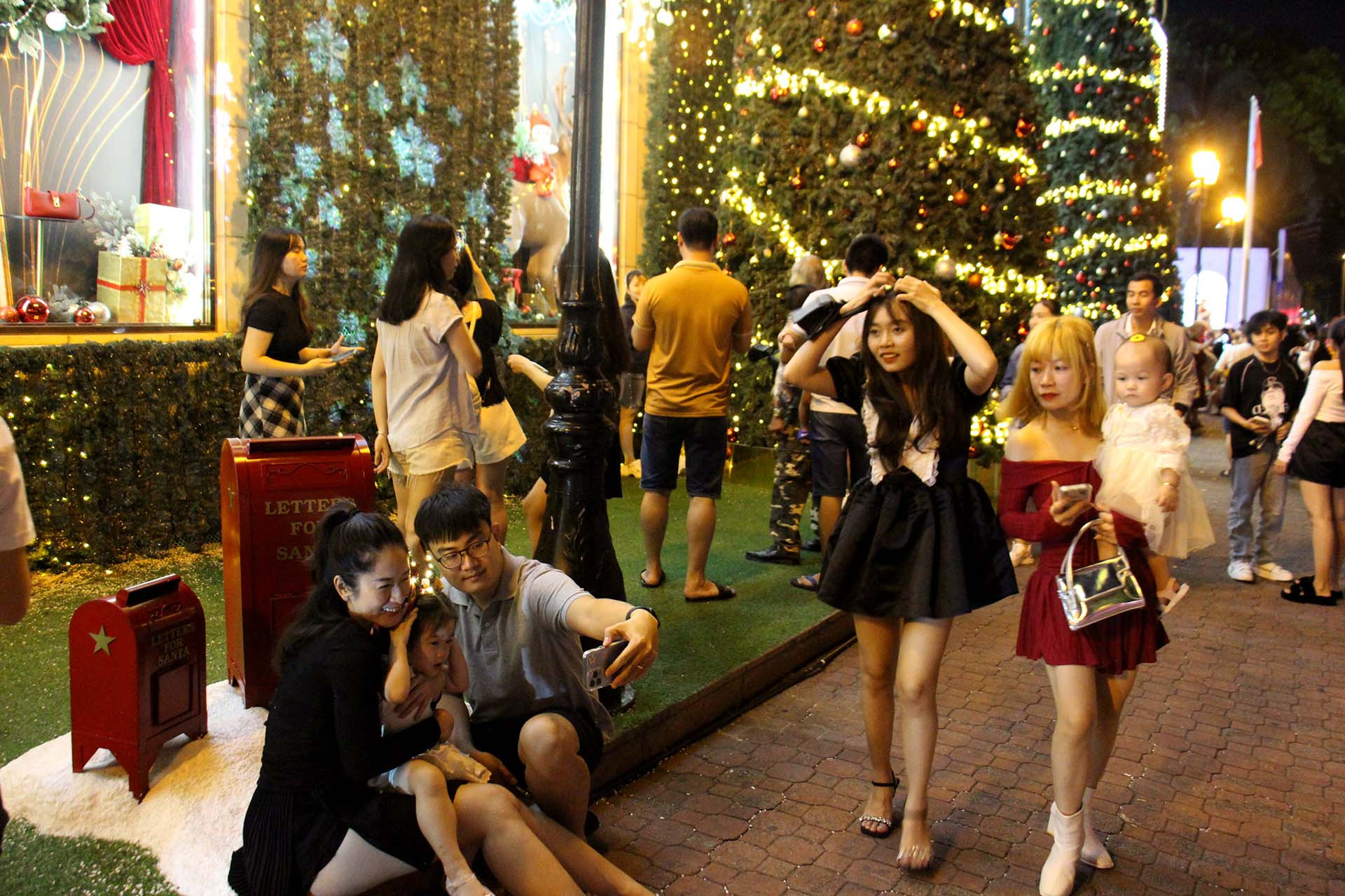 Tại nhiều trung tâm thương mại như Diamond Plaza, Takashimaya, nhiều gia đình, bạn trẻ rủ nhau đi chụp ảnh dưới các cây thông Noel trước thềm Giáng sinh.