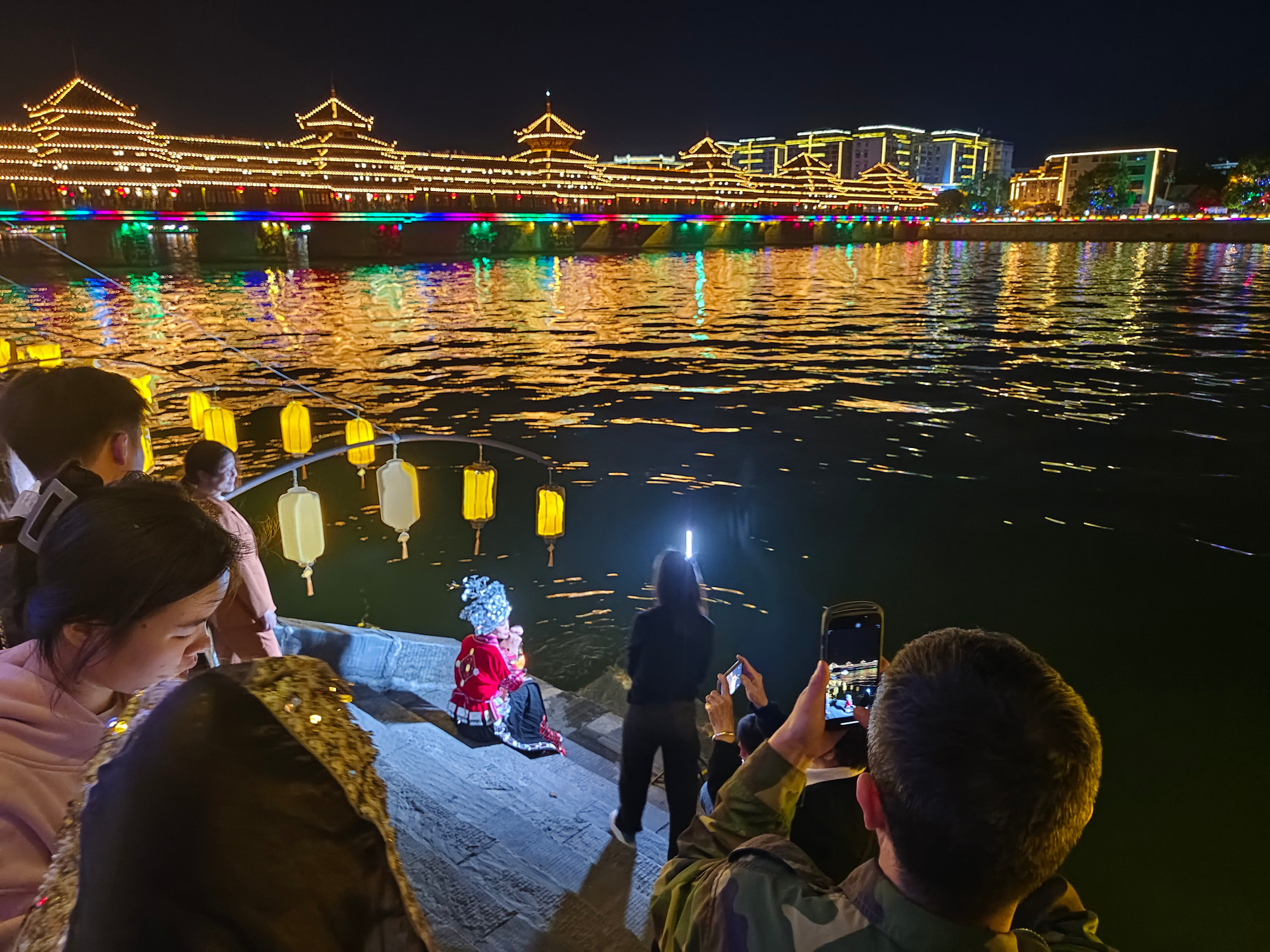 Du khách với thiếu nữ dân tộc Động trong trang phục truyền thống.