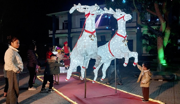 Các em nhỏ thích thú với cỗ xe tuần lộc được bài trí trong khuôn viên thánh đường.