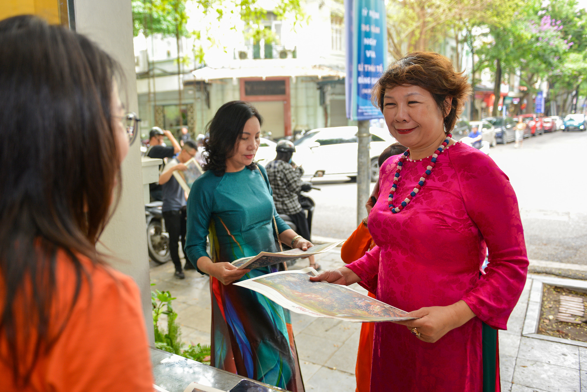 Nhiều phụ nữ mặc áo dài truyền thống đến nhận phụ san.