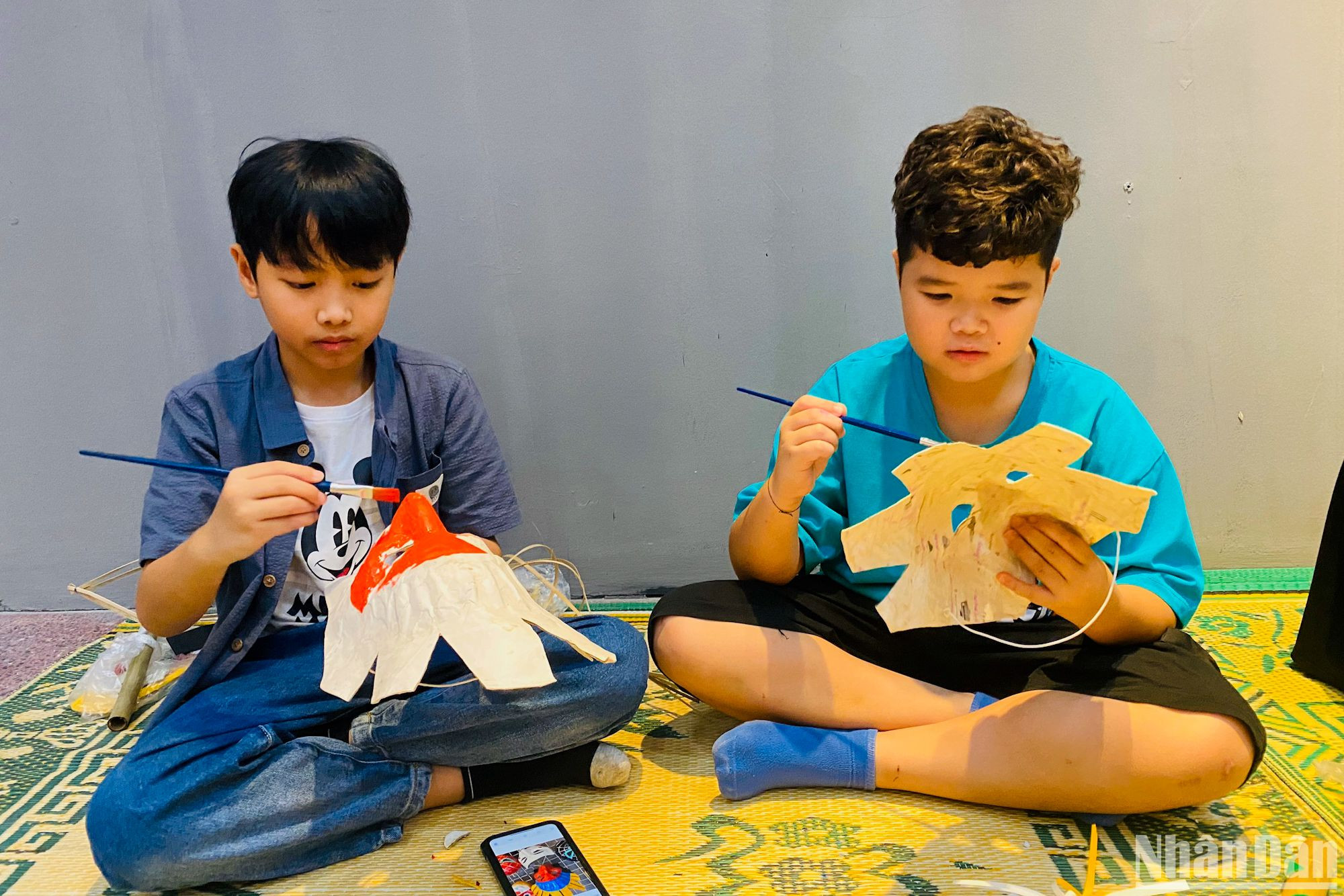 Các bạn nhỏ tô màu cho những chiếc mặt nạ giấy bồi truyền thống.