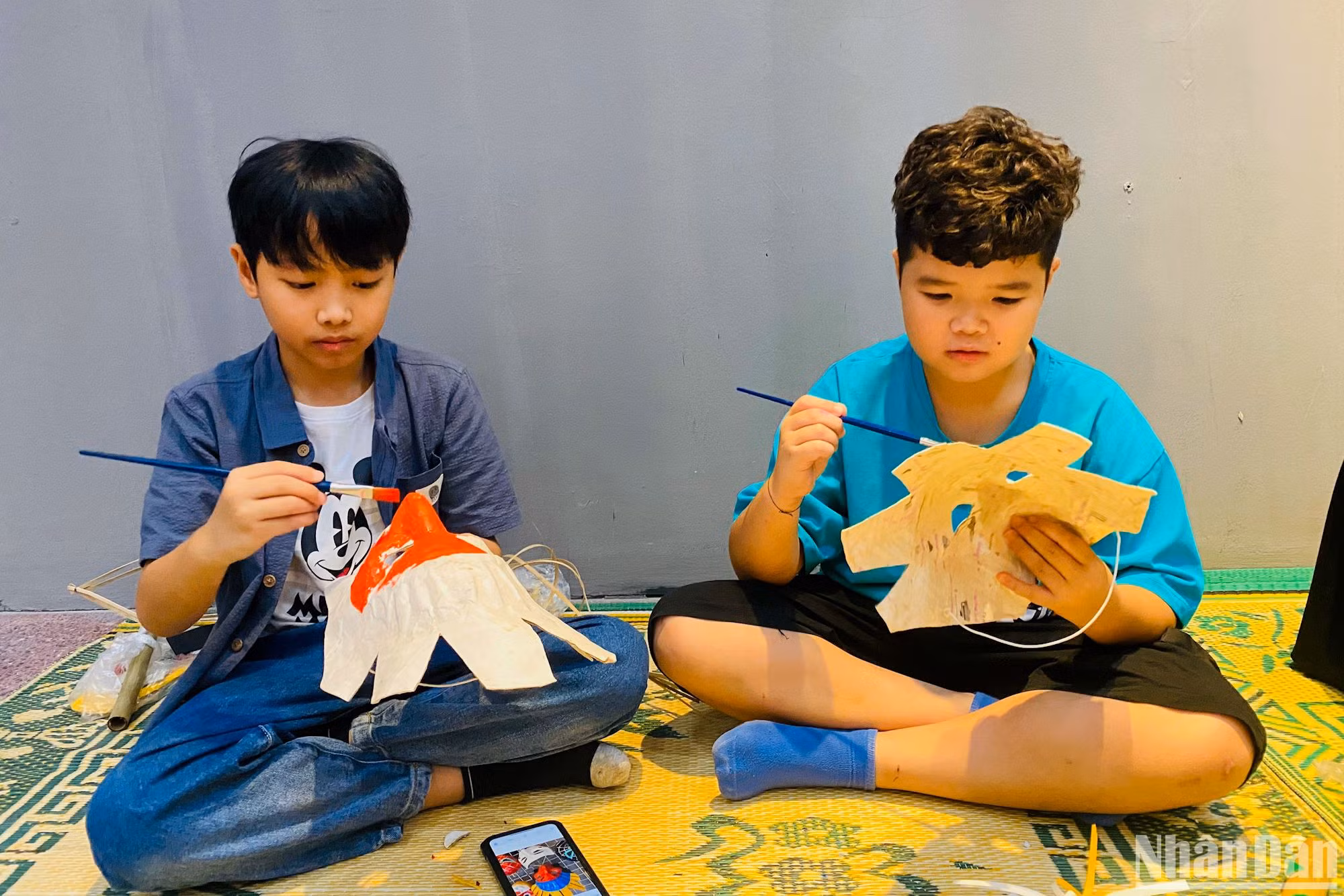 Các bạn nhỏ tô màu cho những chiếc mặt nạ giấy bồi truyền thống.