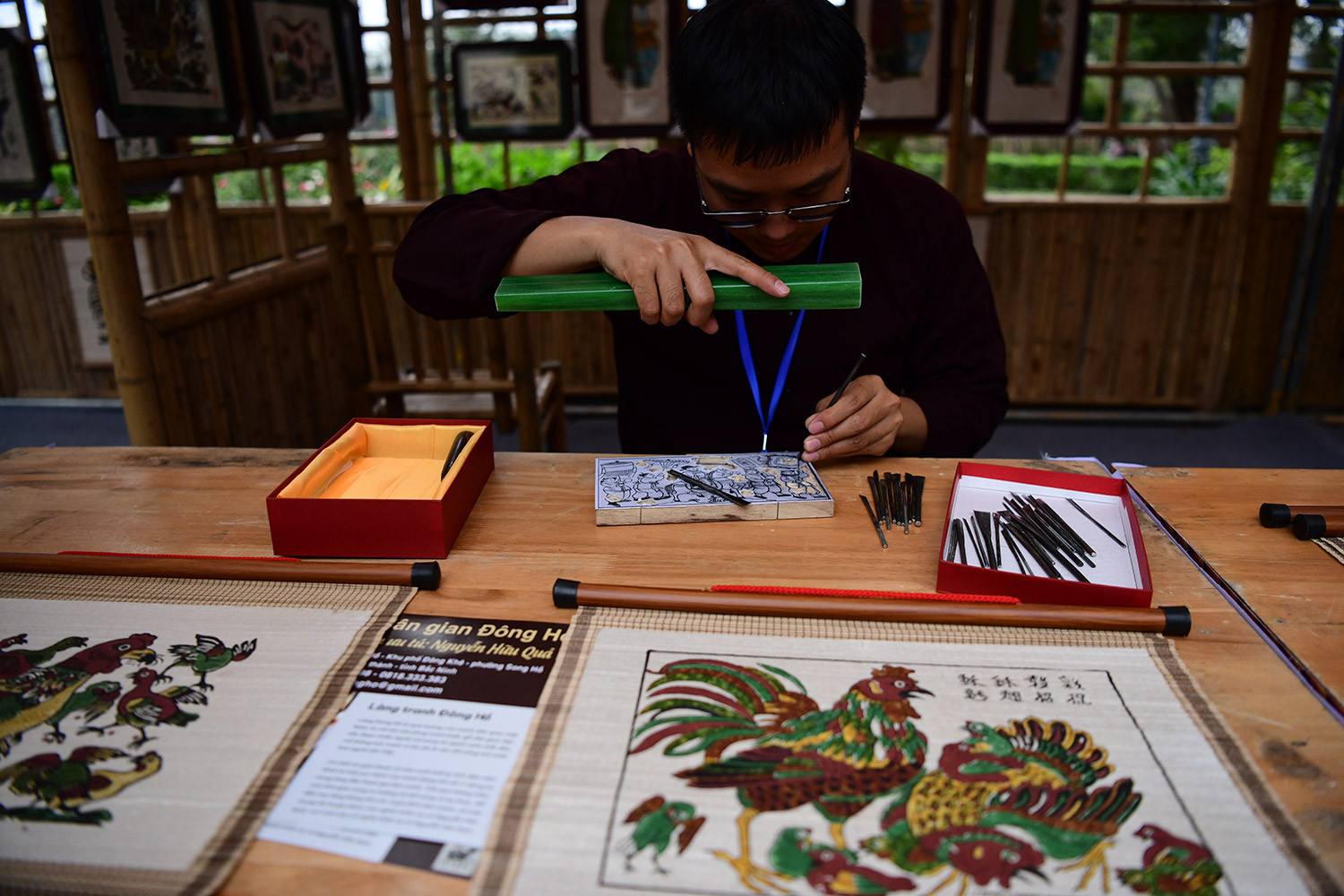 Kỹ thuật làm tranh bằng ván khắc gỗ là một nét tinh hoa của nghệ thuật dân gian, nơi mỗi khuôn in không chỉ lưu giữ dấu ấn bàn tay nghệ nhân mà còn thổi hồn vào từng đường nét. Trong ảnh: nghệ nhân Nguyễn Hữu Đạo (sinh năm 1990, làng Đông Hồ, Thuận Thành, Bắc Ninh) bên những khuôn in tinh xảo, góp phần gìn giữ giá trị truyền thống của dòng tranh Đông Hồ.