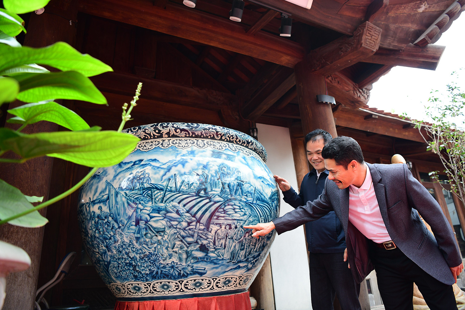 Nghệ nhân Đào Viết Bình (trái ảnh) bên tác phẩm “Hùng ca Điện Biên” (đường kính 1m65, cao 1m1) tái hiện hào khí hào hùng của dân tộc ta qua nghệ thuật gốm sứ.