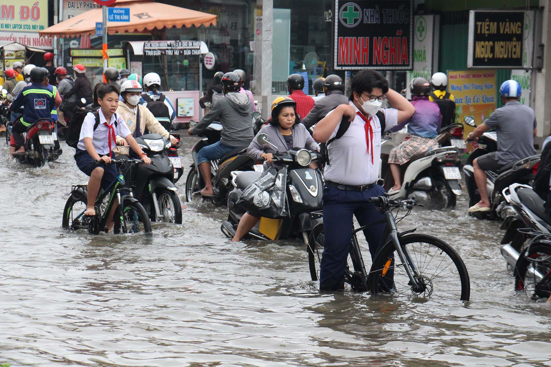 Phụ huynh và học sinh vất vả di chuyển qua các điểm ngập.