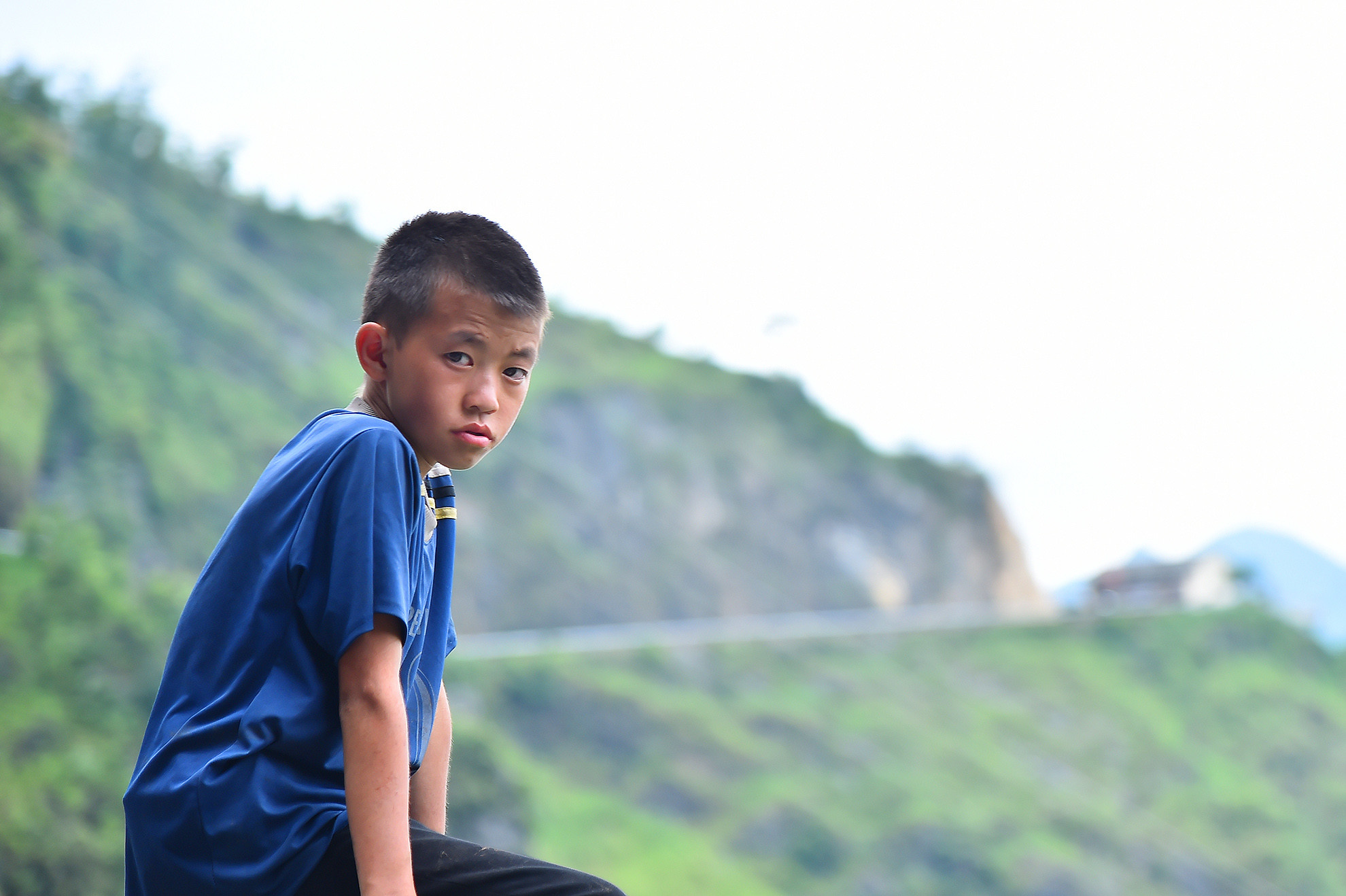 Chiếc xe ô-tô lướt nhanh qua khúc cua và để lại phía sau hình ảnh một cậu bé ngồi trên thành lan can phòng hộ. Chỉ có một mình cậu bé, không có ai bên cạnh nhưng nét mặt đượm buồn chất chứa bao tâm tư như ánh chiều hoàng hôn nơi vùng cao.