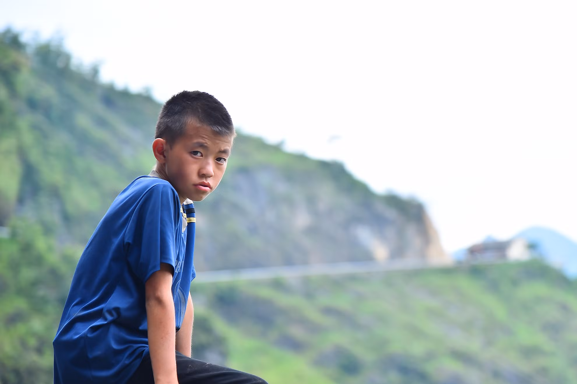 Chiếc xe ô-tô lướt nhanh qua khúc cua và để lại phía sau hình ảnh một cậu bé ngồi trên thành lan can phòng hộ. Chỉ có một mình cậu bé, không có ai bên cạnh nhưng nét mặt đượm buồn chất chứa bao tâm tư như ánh chiều hoàng hôn nơi vùng cao.