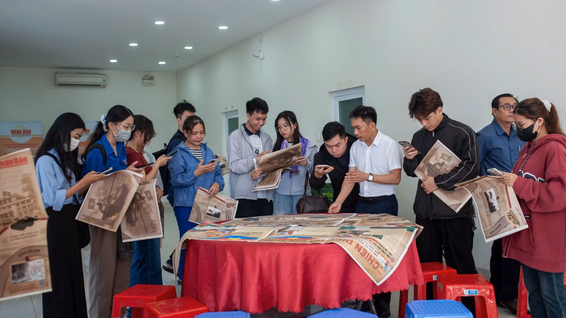 Lãnh đạo Cơ quan Đại diện Báo Nhân Dân tại miền trung-Tây Nguyên hướng dẫn độc giả trải nghiệm phụ san đặc biệt bằng công nghệ.