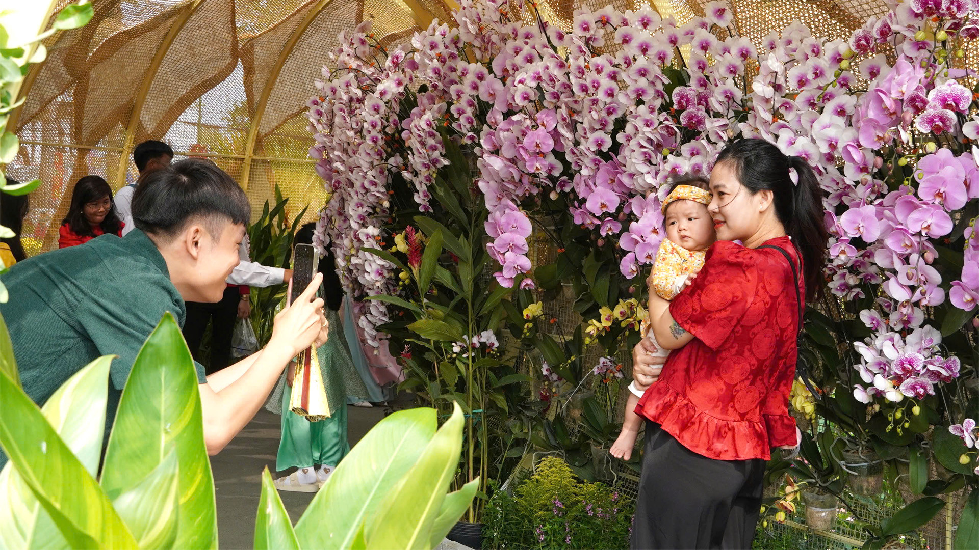 Du khách tham quan, chụp ảnh tại đại cảnh Chuyển mình vươn xa, được thiết kế uốn lượn như thân loài rắn, biểu trưng của sự đổi mới, chuyển mình, có trưng bày hơn 2.000 chậu hoa lan.