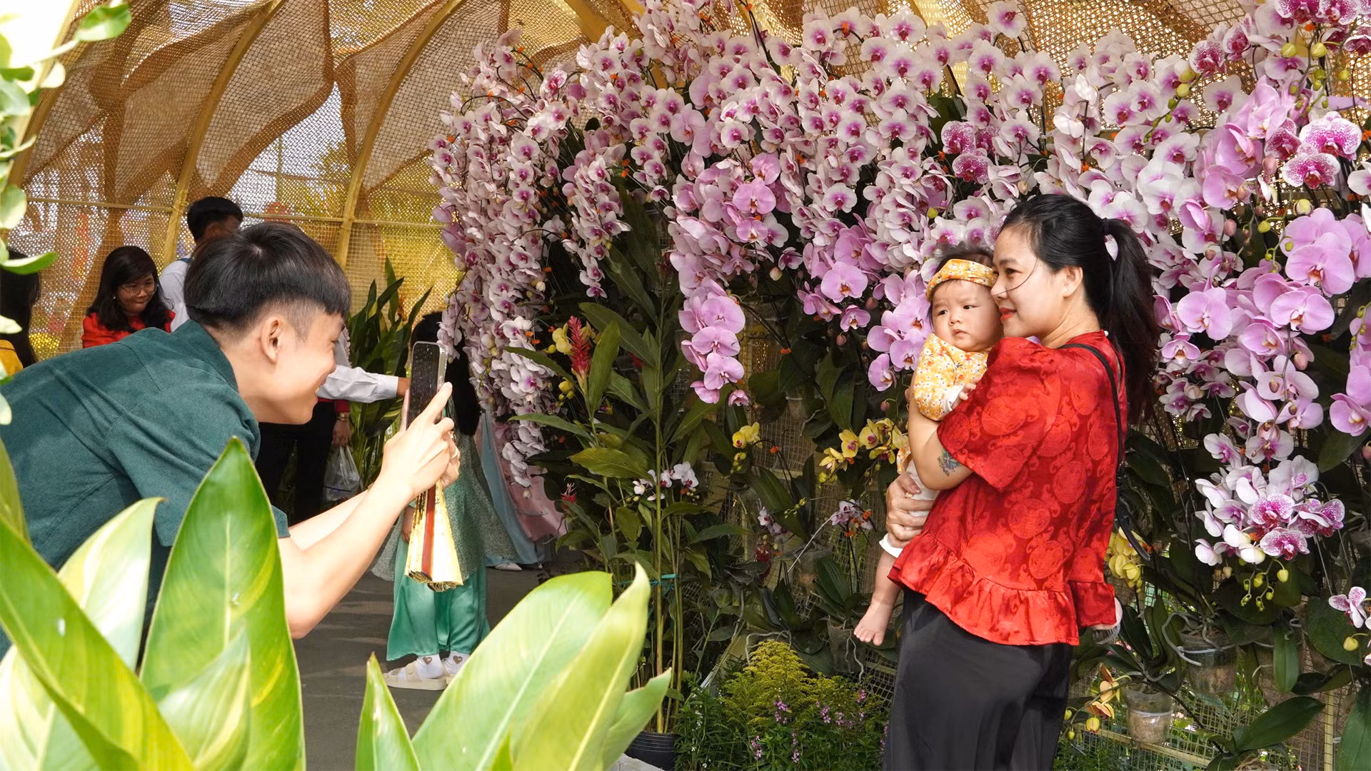 Du khách tham quan, chụp ảnh tại đại cảnh Chuyển mình vươn xa, được thiết kế uốn lượn như thân loài rắn, biểu trưng của sự đổi mới, chuyển mình, có trưng bày hơn 2.000 chậu hoa lan.