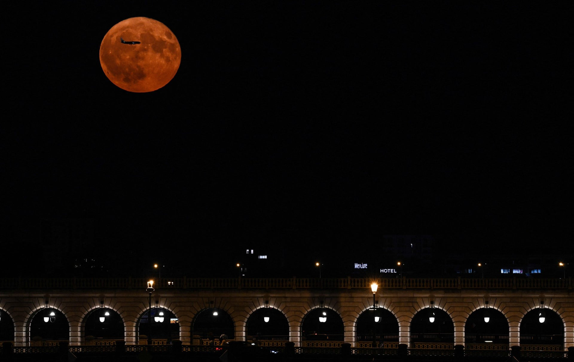 Một chiếc máy bay bay ngang qua siêu trăng trên bầu trời thủ đô Paris, Pháp. (Ảnh: Getty Images)