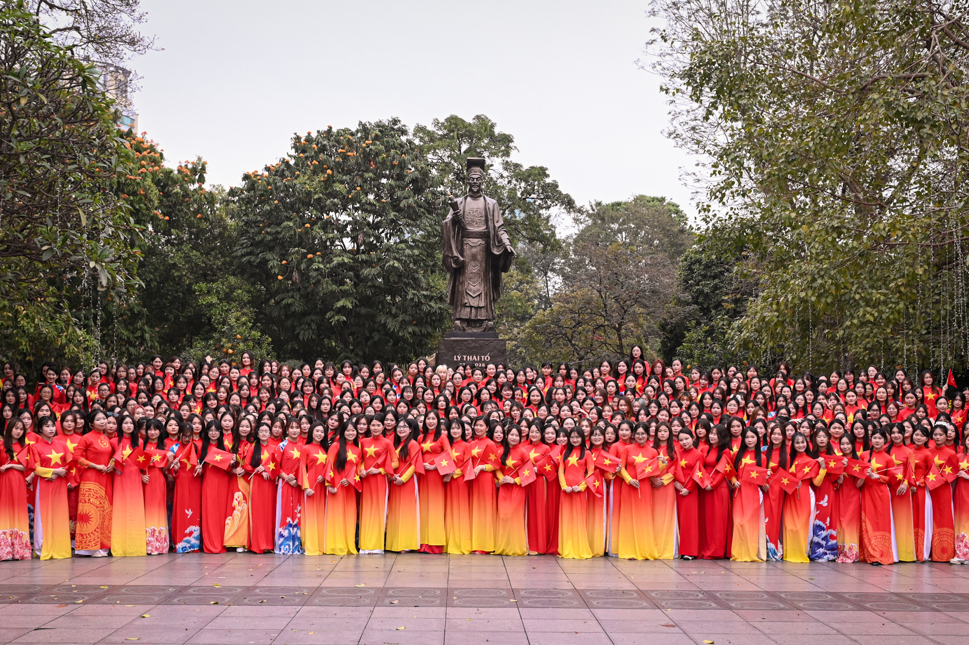 500 nữ sinh viên Học viện Phụ nữ Việt Nam trong trang phục áo dài cờ đỏ sao vàng chụp ảnh lưu niệm tại tượng đài Lý Thái Tổ.