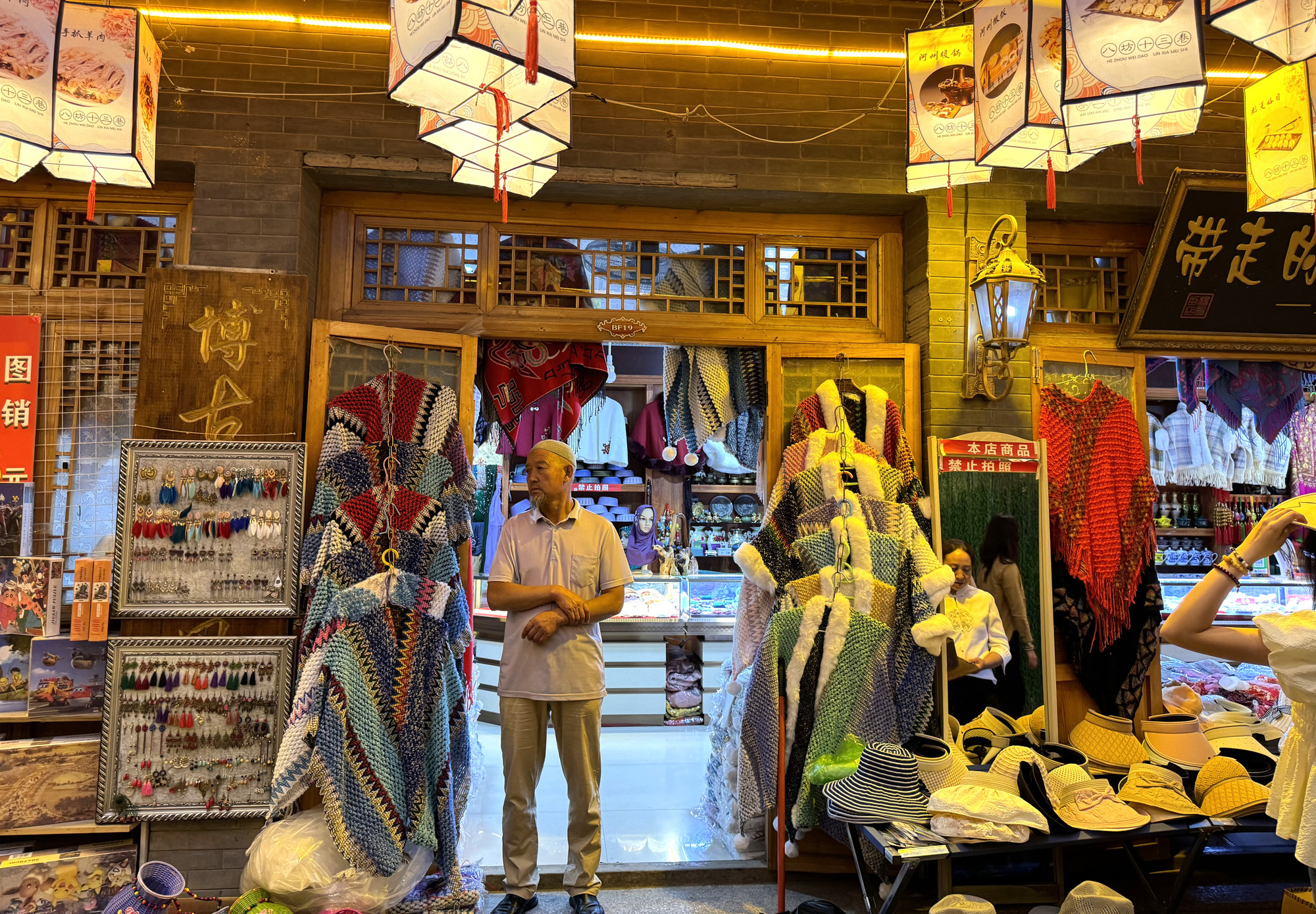 Một người dân tộc Hồi trước cửa hàng bán trang phục bản địa.