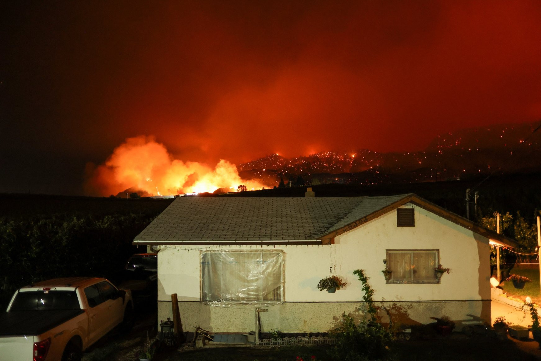 Đám cháy rừng Eagle Bluffs thiêu rụi phía sau một ngôi nhà sau khi đám cháy lan qua biên giới Canada-Mỹ. Ảnh: Reuters.