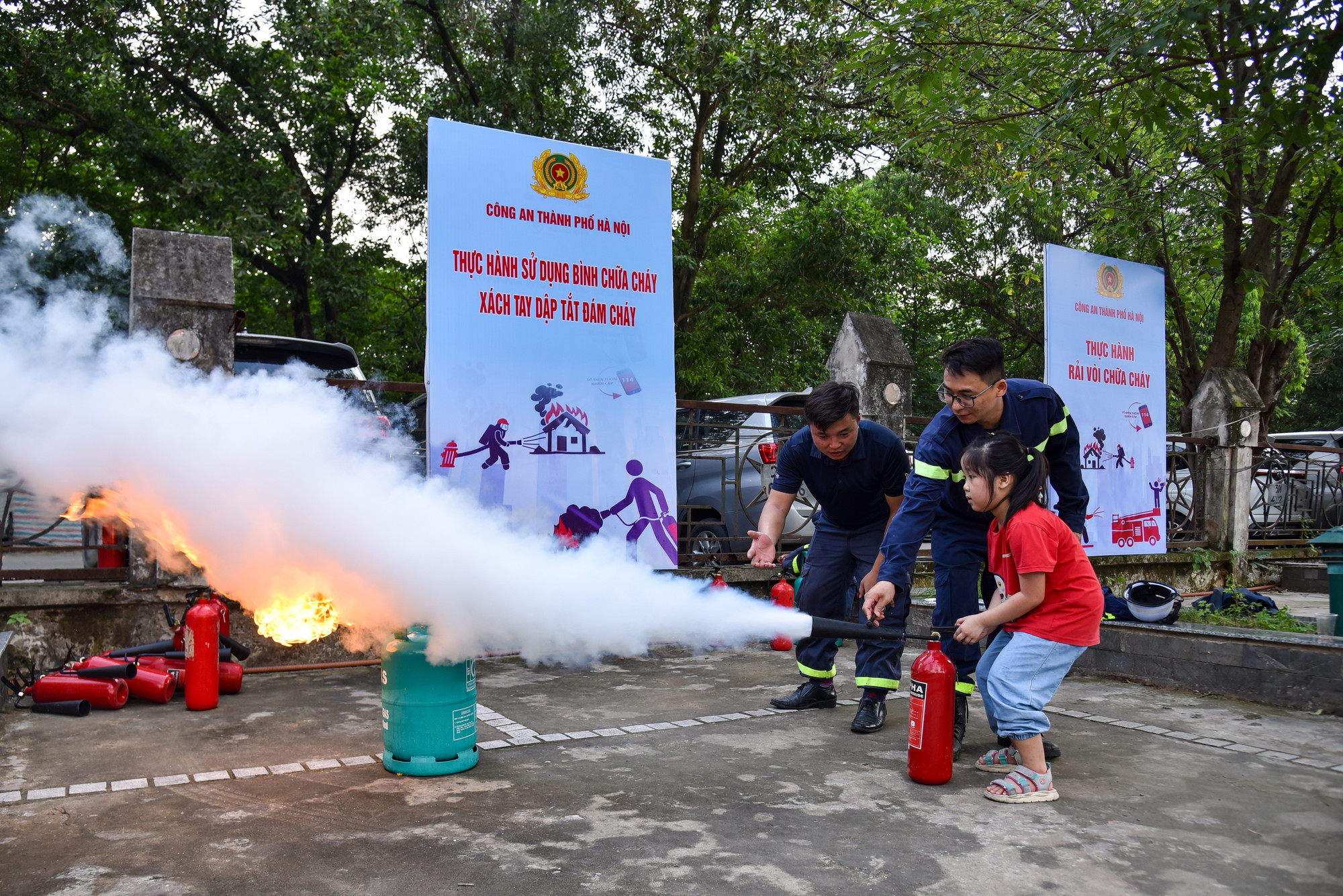 Một bạn nhỏ được các chiến sĩ hướng dẫn tận tình dập tắt đám cháy bằng bình cứu hỏa.