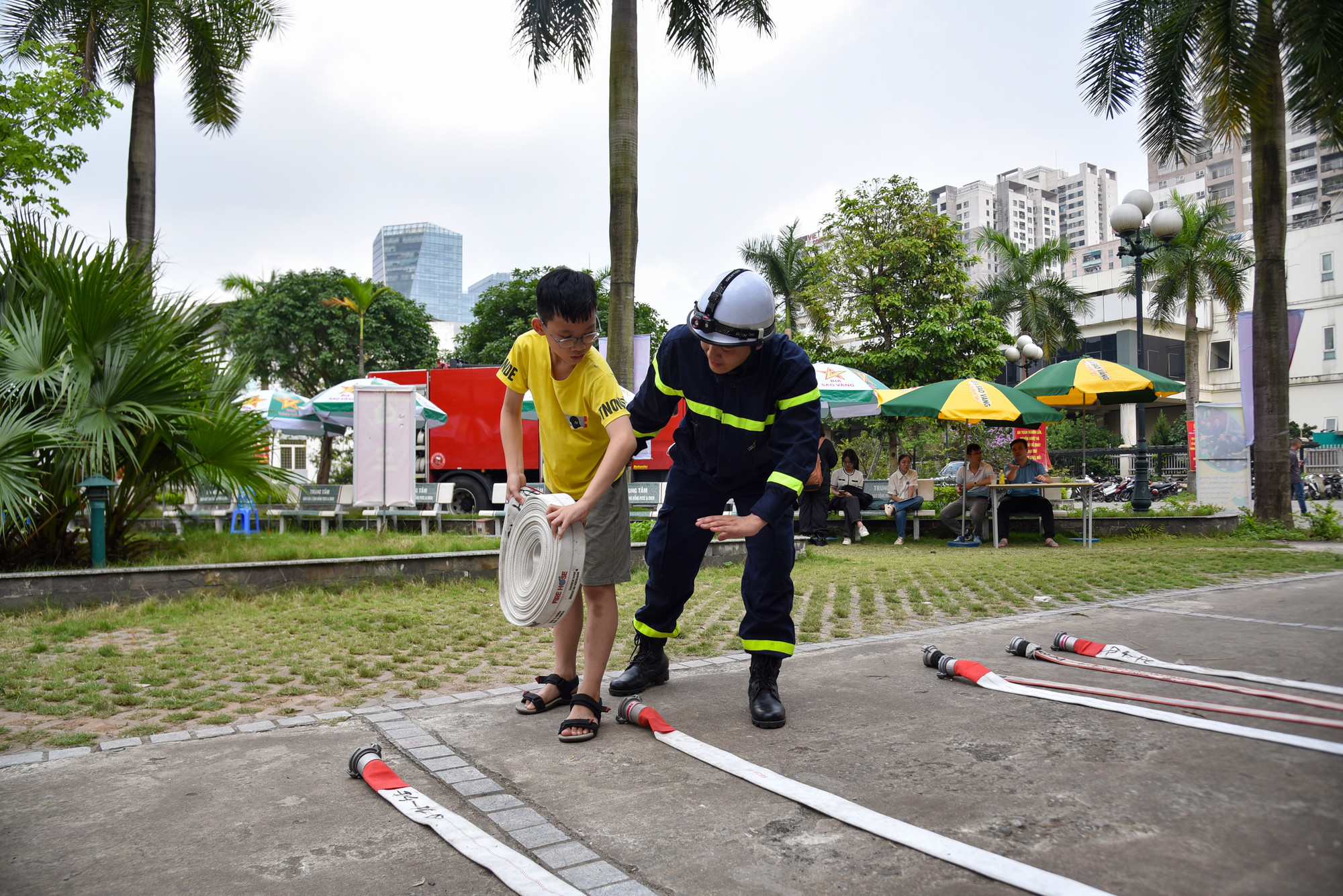 Một bạn nhỏ được các chiến sĩ Phòng cháy chữa cháy hướng dẫn thực hành rải vòi chữa cháy.