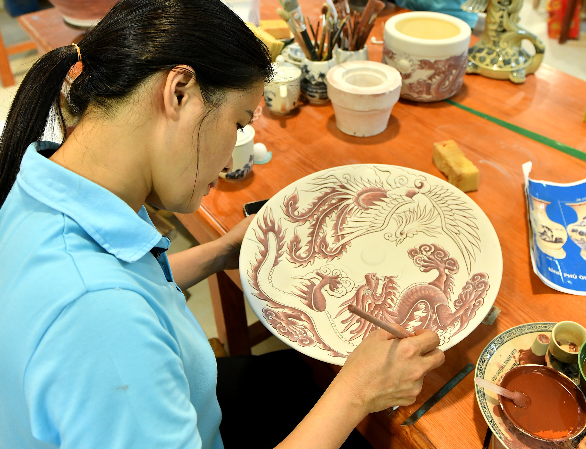 Nghệ nhân vẽ hình lên sản phẩm gốm.
