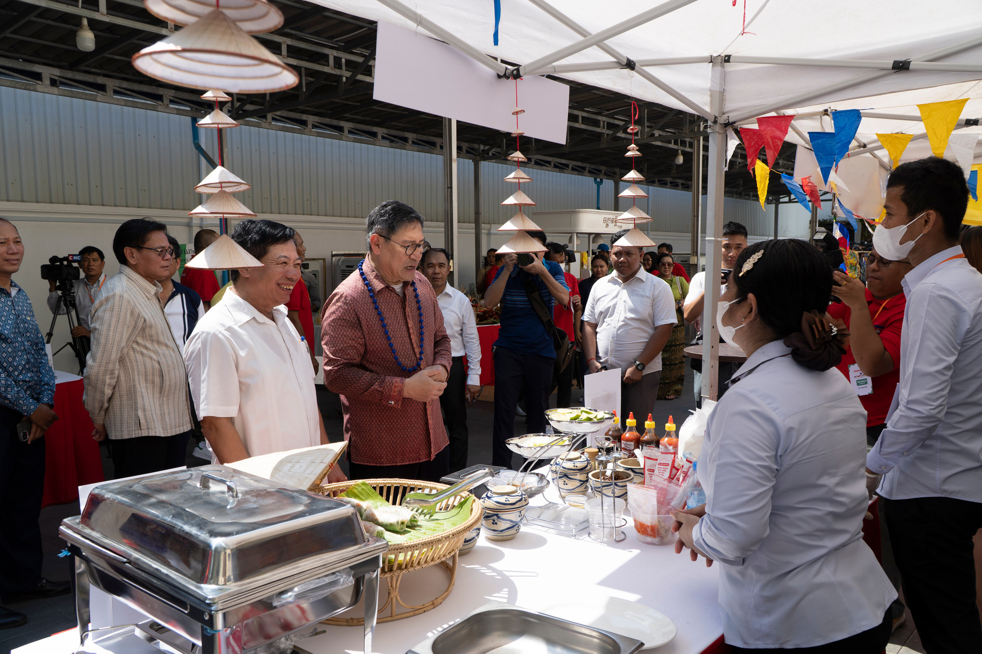 Đại sứ Nguyễn Huy Tăng (áo trắng) hướng dẫn Phó Thủ tướng Campuchia Sok Chenda Sophea thăm gian hàng ẩm thực Việt Nam. (Ảnh: Nguyễn Hiệp) Đại sứ Nguyễn Huy Tăng (áo trắng) hướng dẫn Phó Thủ tướng Campuchia Sok Chenda Sophea thăm gian hàng ẩm thực Việt Nam. (Ảnh: Nguyễn Hiệp)