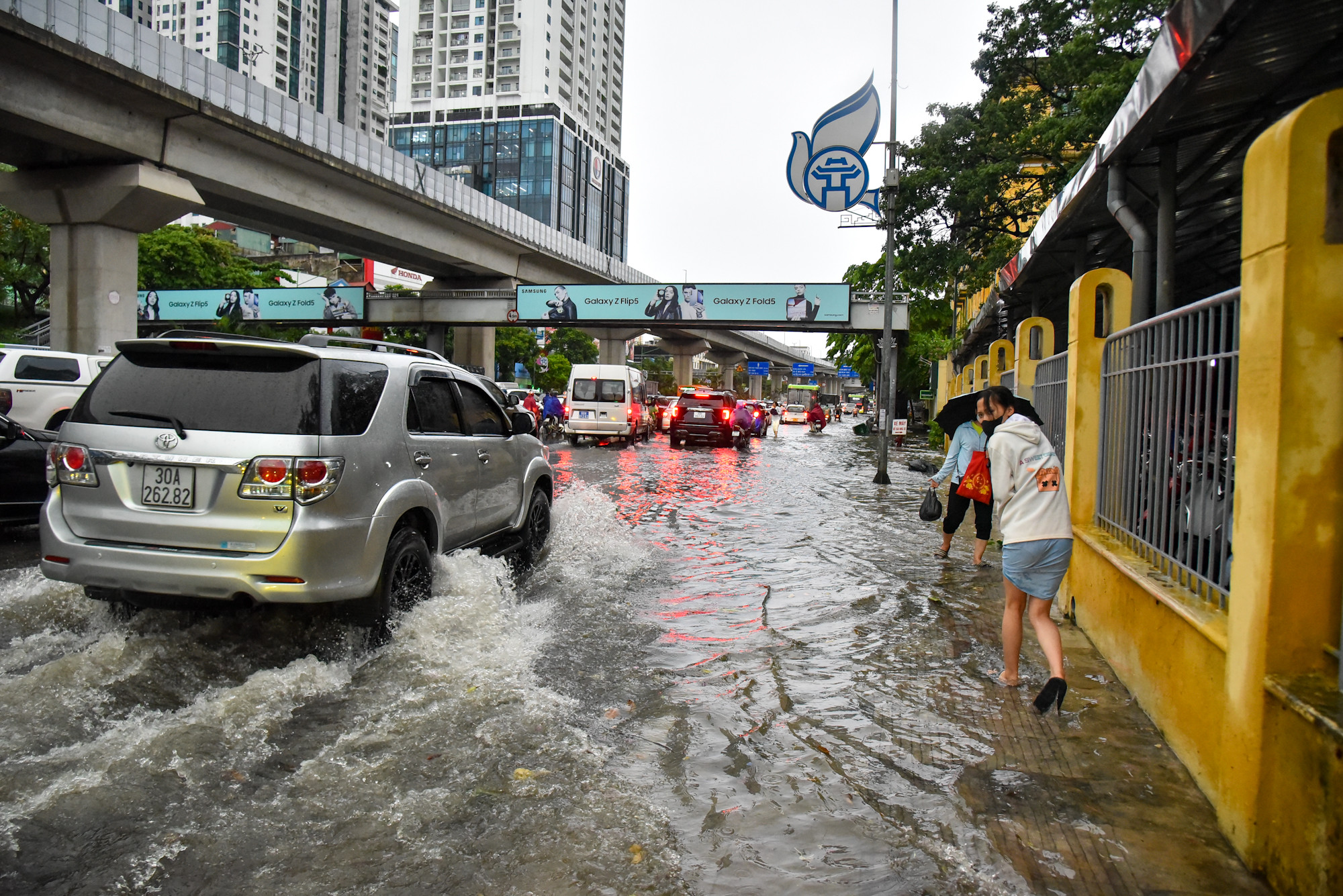 Nước tràn lên vỉa hè khiến việc đi lại của người dân trở nên khó khăn.