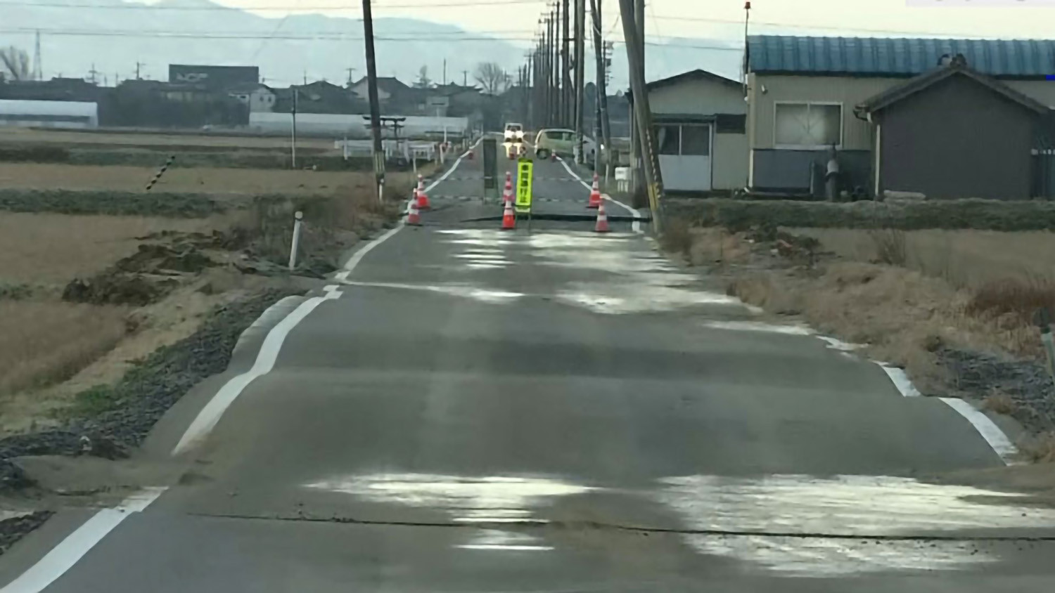 Con đường chạy qua cánh đồng lúa ở vùng nông thôn thuộc phường Nishikan, thành phố Niigata, tỉnh Niigata đã bị cấm lưu thông sau khi có vết nứt khiến mặt đường không bằng phẳng. Một số cột điện bị nghiêng hoặc đổ xuống đường. Ảnh: NHK