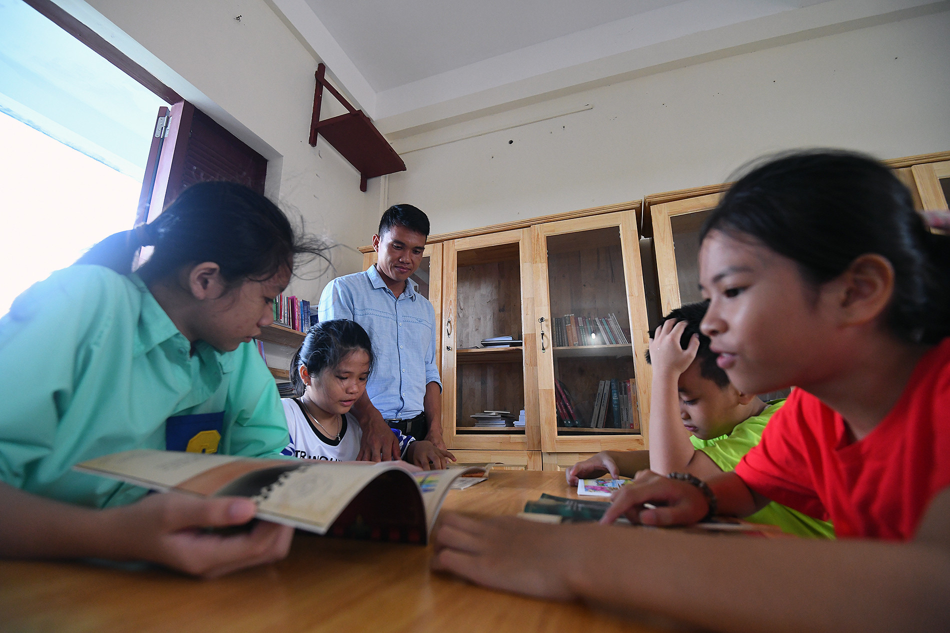 Thiếu nhi đảo Sinh Tồn được thầy giáo hướng dẫn đọc sách ngoài giờ học tại thư viện trên đảo.