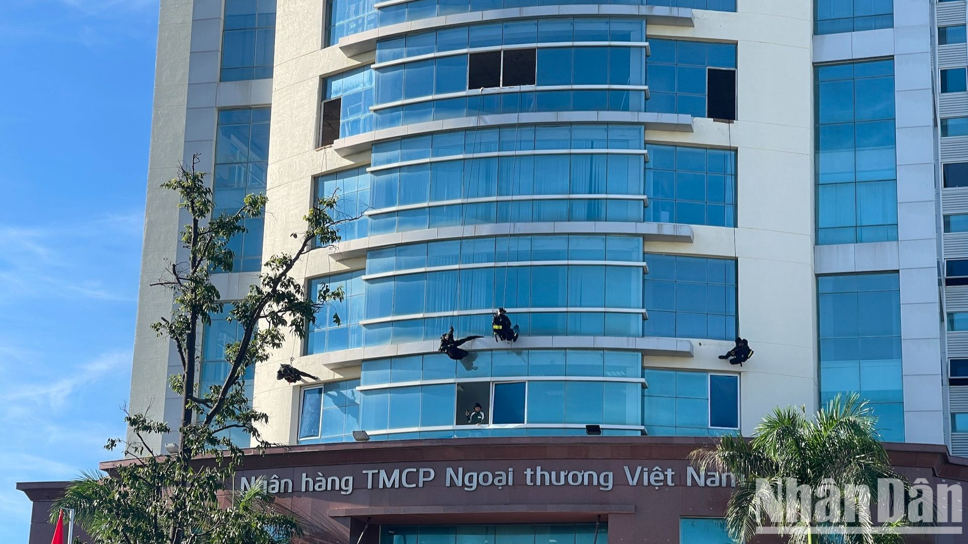 Công an đang đu dây thang xuống để đi vào bên trong tòa nhà.