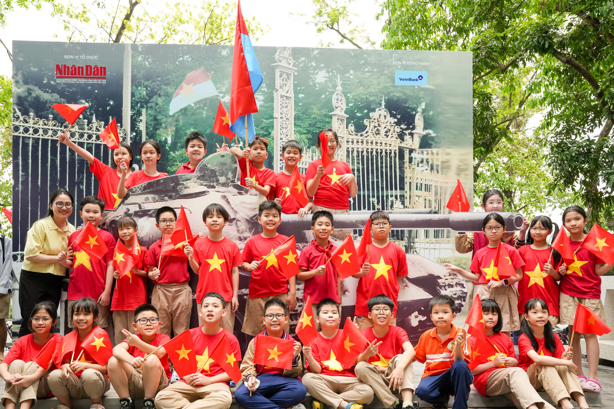 Cô và trò Trường tiểu học Trần Quốc Toản chụp ảnh cùng mô hình chiếc xe tăng 390 đã húc đổ cổng chính Dinh Độc Lập.