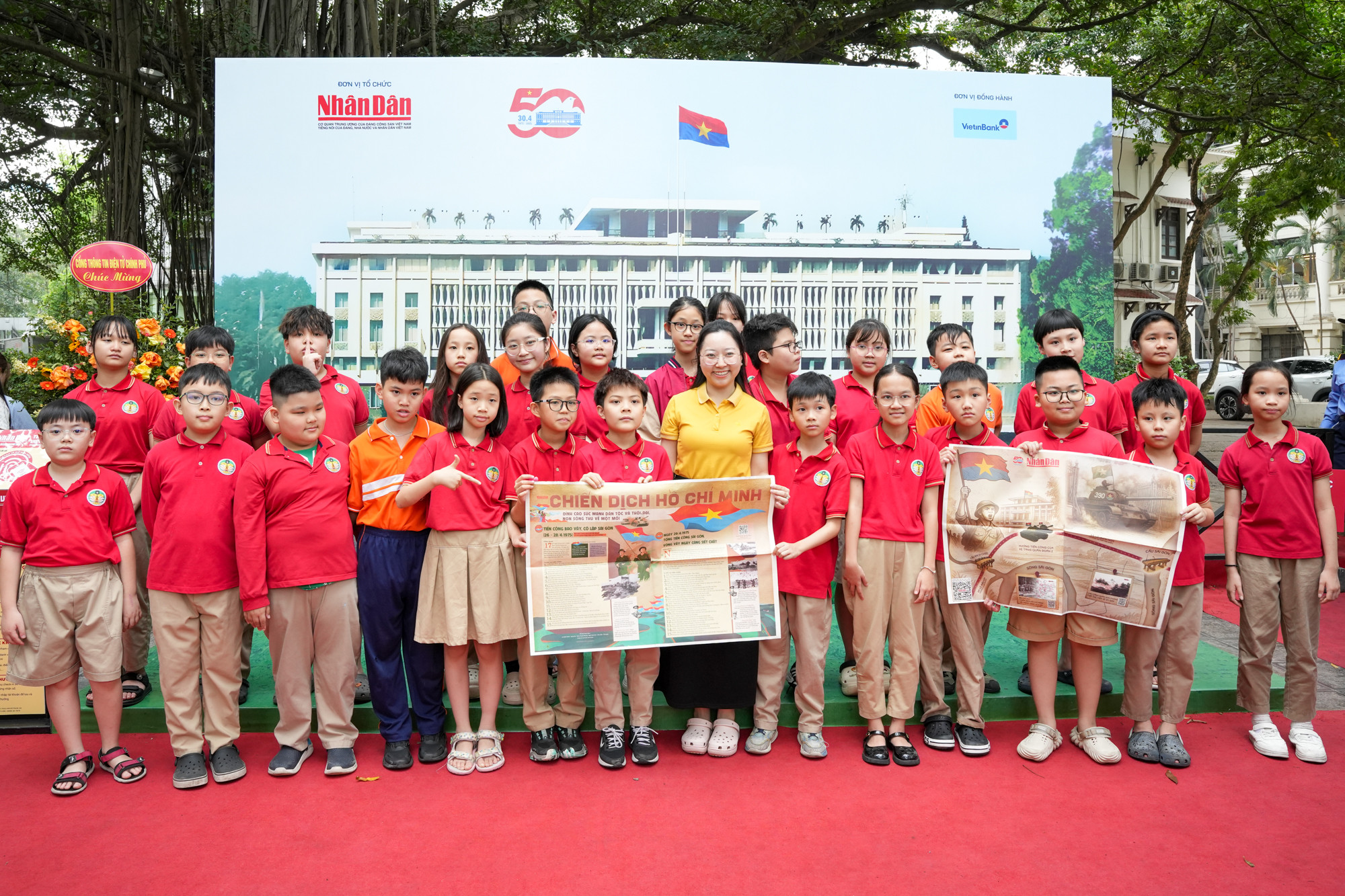 Cô giáo và học sinh Trường tiểu học Tràng An chụp ảnh cùng ấn phẩm thông tin đặc biệt của Báo Nhân Dân.