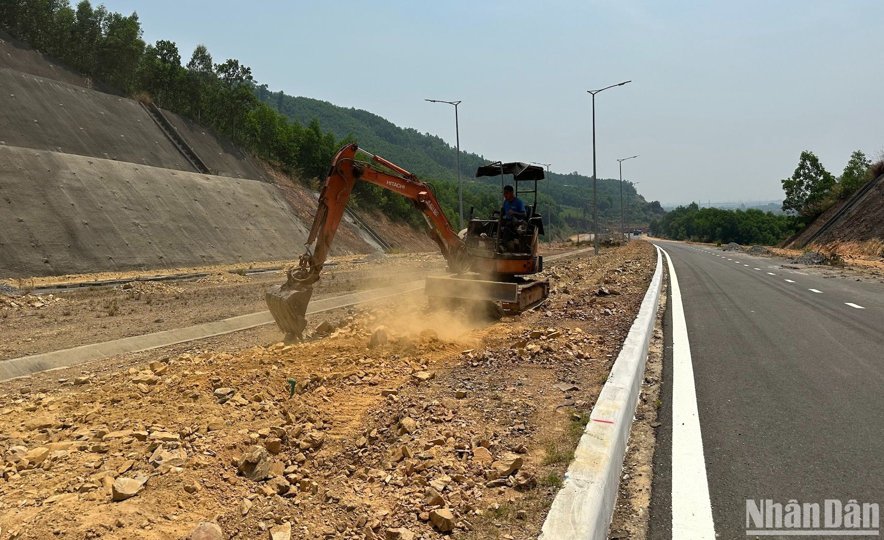 Một công nhân đang tiến hành làm tơi đất để phục vụ việc trồng cây trên tuyến đường.