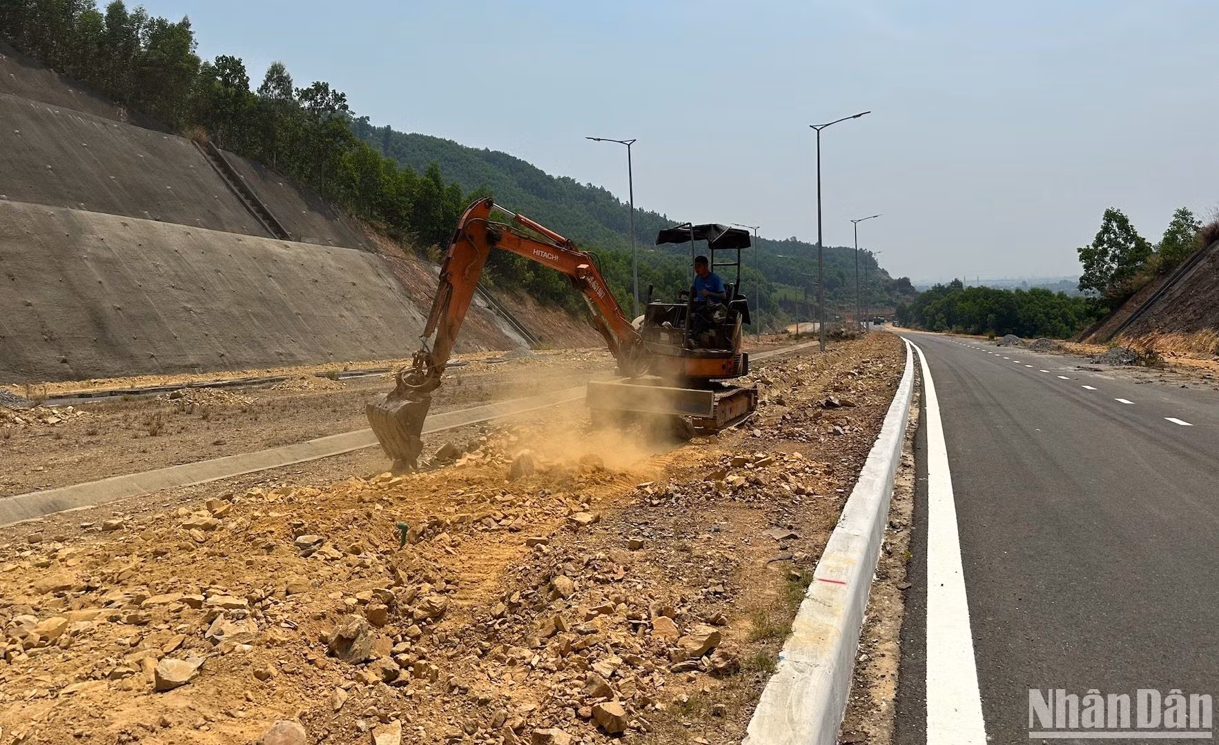 Một công nhân đang tiến hành làm tơi đất để phục vụ việc trồng cây trên tuyến đường.
