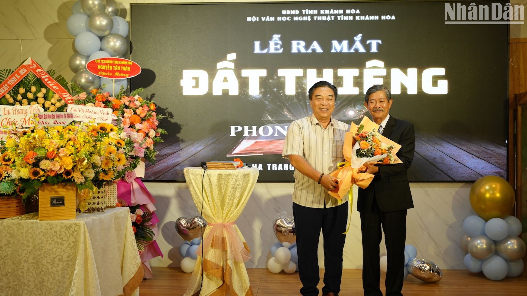 Nhà báo Phong Nguyên tặng hoa cảm ơn nhà báo Đoàn Minh Long, Chủ tịch Hội Nhà báo tỉnh Khánh Hòa, tác giả thiết kế bìa cuốn sách Đất thiêng. (Ảnh: ANH ĐÀO)