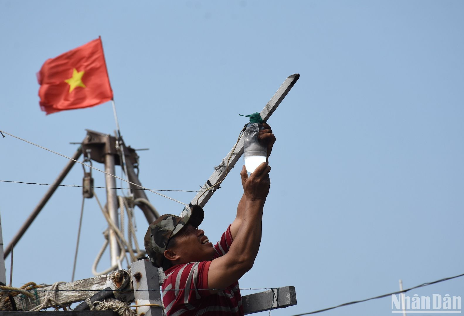 Một ngư dân đang kiểm tra, lắp lại bóng đèn trên tàu cá.