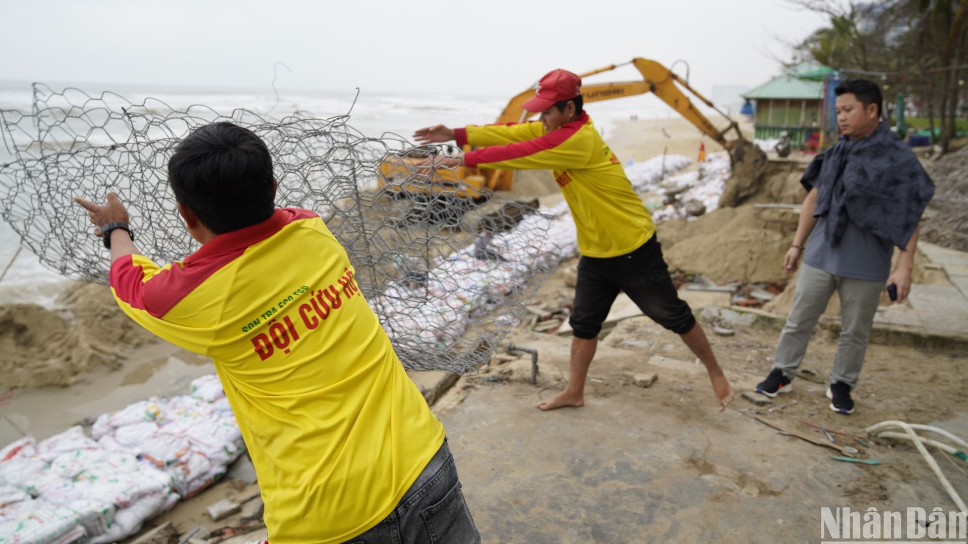 Lực lượng cứu hộ biển Đà Nẵng đang triển khai dây thép gai bao quanh các bao tải cát. (Ảnh: ANH ĐÀO) Lực lượng cứu hộ biển Đà Nẵng đang triển khai dây thép gai bao quanh các bao tải cát. (Ảnh: ANH ĐÀO)