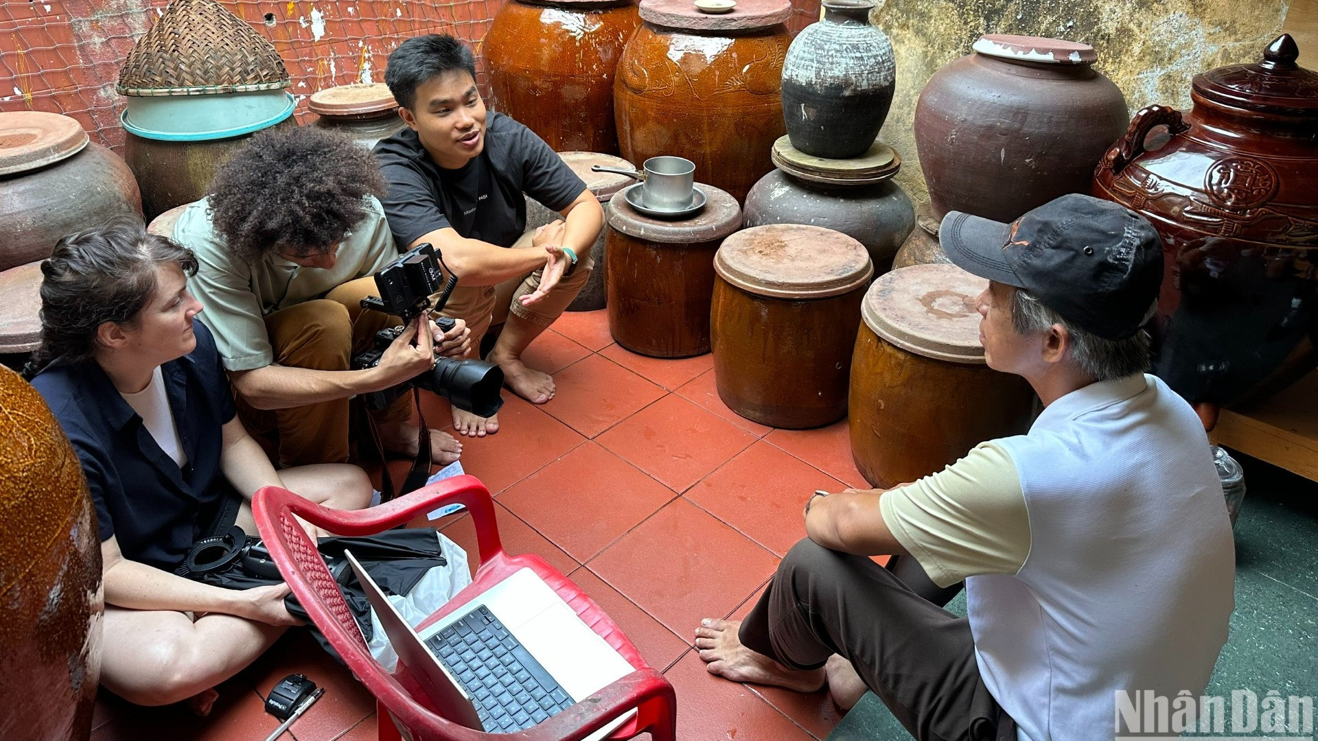 Ông Huỳnh Văn Mười (59 tuổi, trú phường Mân Thái, quận Sơn Trà, Đà Nẵng) đang giới thiệu về văn hóa biển và nghề làm nước mắm nhĩ của ngư dân làng biển Mân Thái với du khách nước ngoài. (Ảnh: ANH ĐÀO)